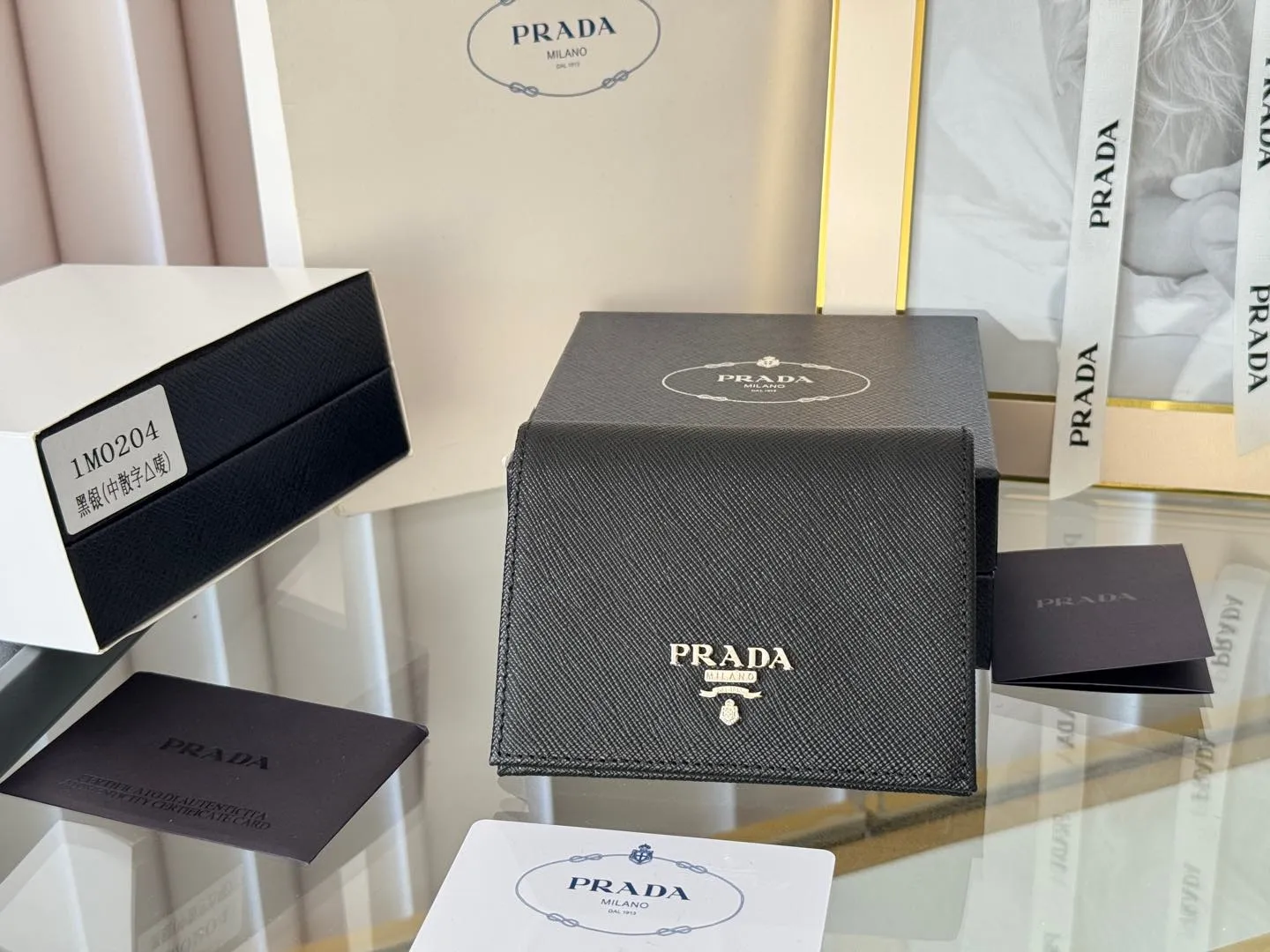 Prada women's two-fold short clip, with coin pocket and coin pocket. Model 1M0204, cross-grain cowhide. Size: 11.2x9.5cm. Simple and practical to enhance personal taste.