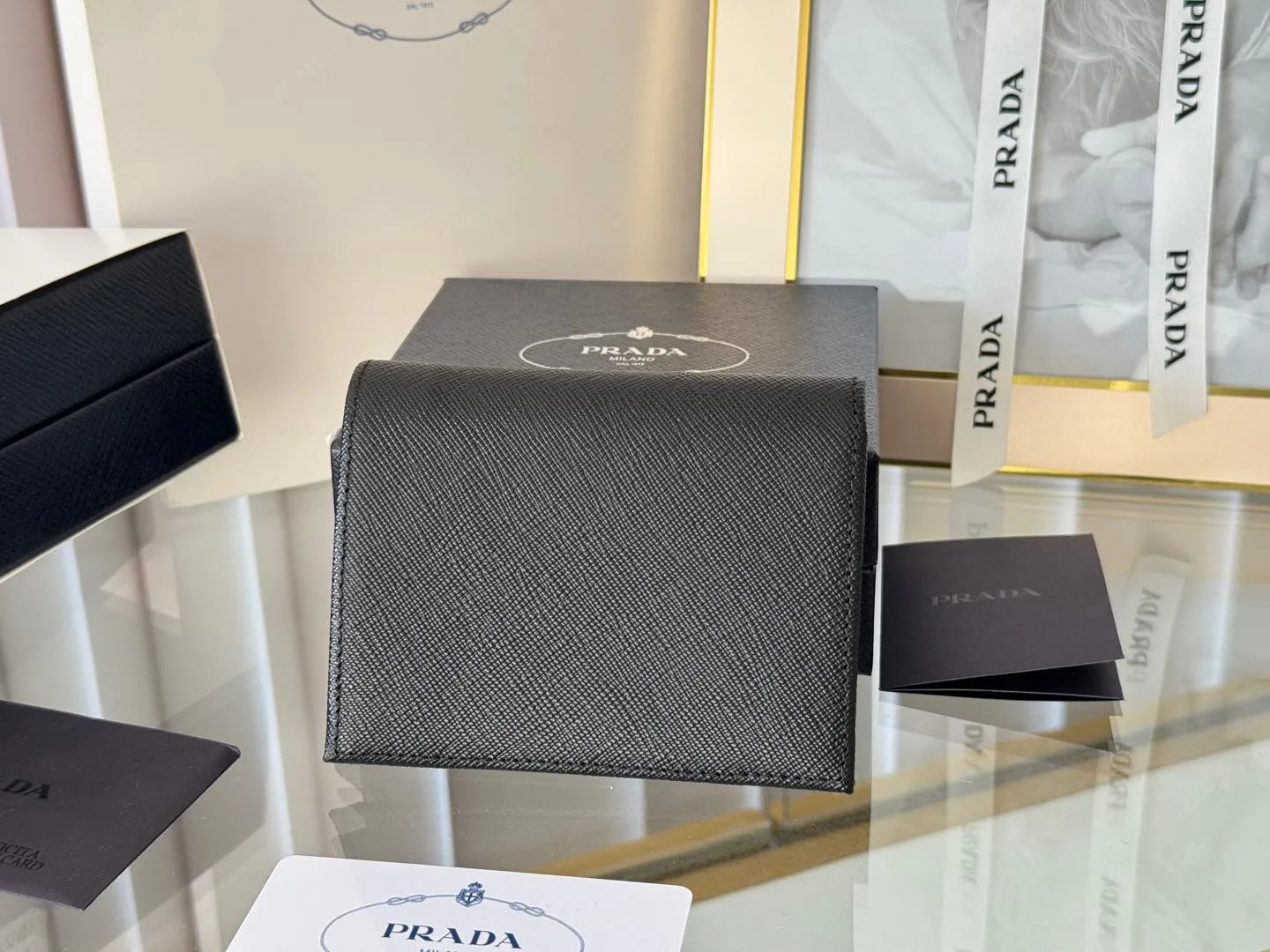 Prada women's two-fold short clip, with coin pocket and coin pocket. Model 1M0204, cross-grain cowhide. Size: 11.2x9.5cm. Simple and practical to enhance personal taste.