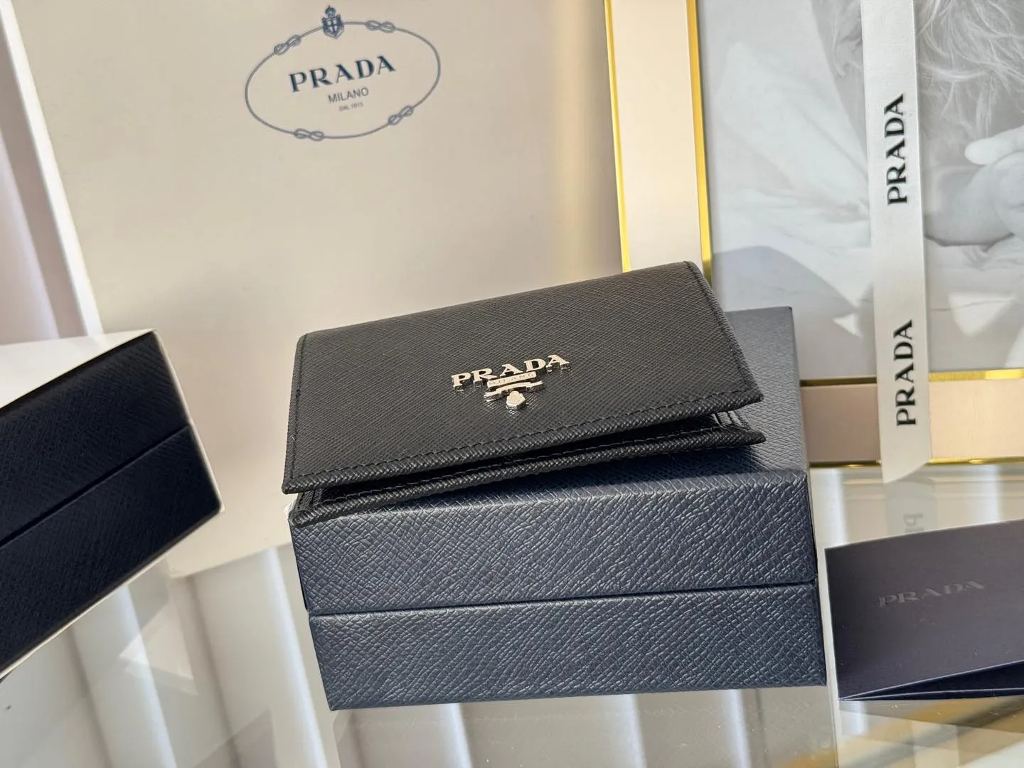 Prada women's two-fold short clip, with coin pocket and coin pocket. Model 1M0204, cross-grain cowhide. Size: 11.2x9.5cm. Simple and practical to enhance personal taste.