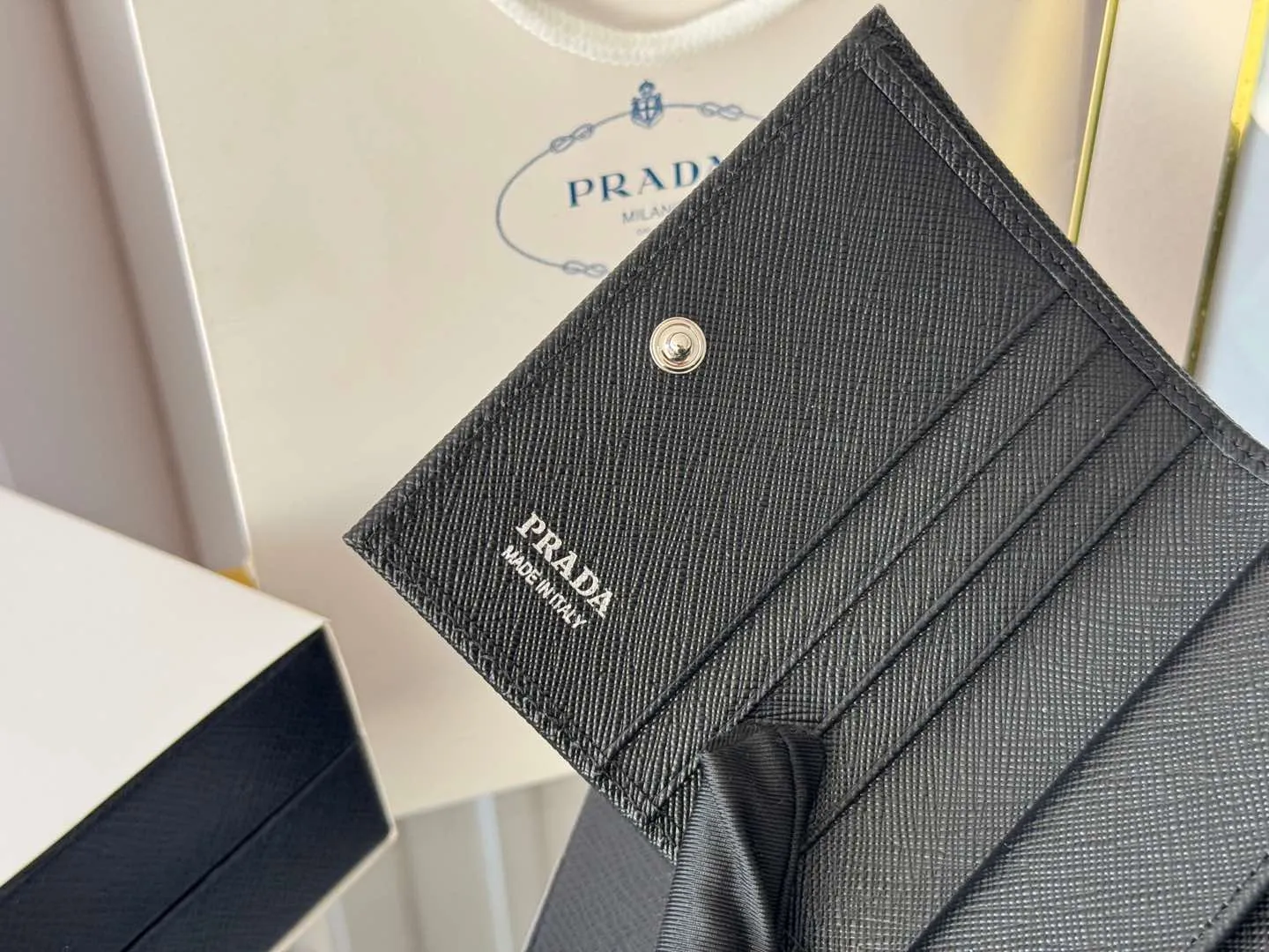 Prada women's two-fold short clip, with coin pocket and coin pocket. Model 1M0204, cross-grain cowhide. Size: 11.2x9.5cm. Simple and practical to enhance personal taste.