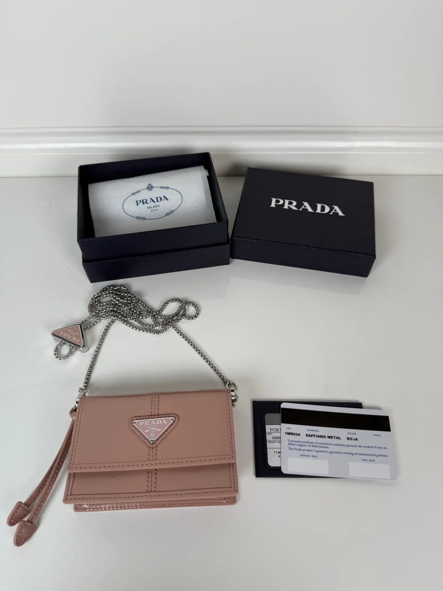 💰900; P Home ➡️Multifunctional mini backpack for women, model 1MR034, flip-top card holder with detachable Saffiano leather shoulder strap, metal triangular micro-mark decorating the front, size 11.5 x8 x2.5cm, two card slots inside, snap closure, in summer it is a mini backpack, in winter it can be turned into a small card holder by removing the shoulder strap, super practical and worth owning👍