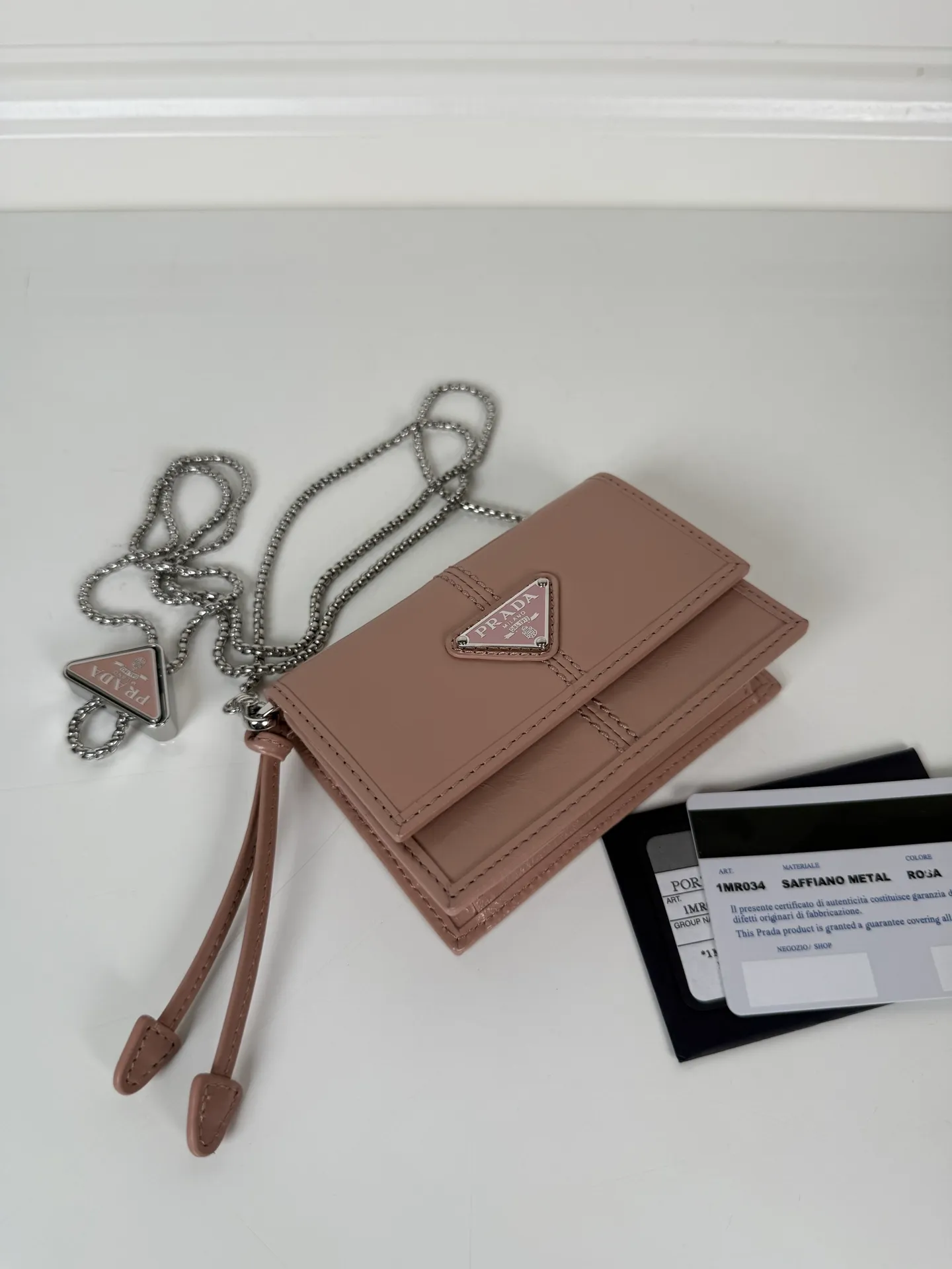 💰900; P Home ➡️Multifunctional mini backpack for women, model 1MR034, flip-top card holder with detachable Saffiano leather shoulder strap, metal triangular micro-mark decorating the front, size 11.5 x8 x2.5cm, two card slots inside, snap closure, in summer it is a mini backpack, in winter it can be turned into a small card holder by removing the shoulder strap, super practical and worth owning👍
