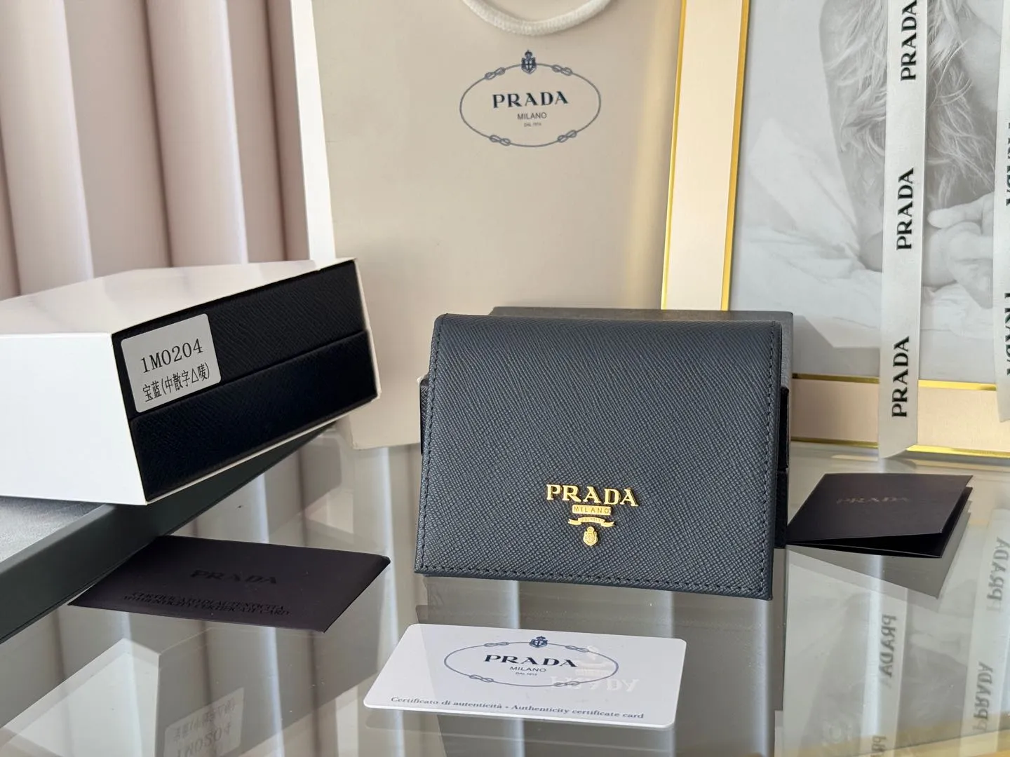 Prada women's two-fold short clip, with coin pocket and coin pocket. Model 1M0204, cross-grain cowhide. Size: 11.2x9.5cm. Simple and practical to enhance personal taste.