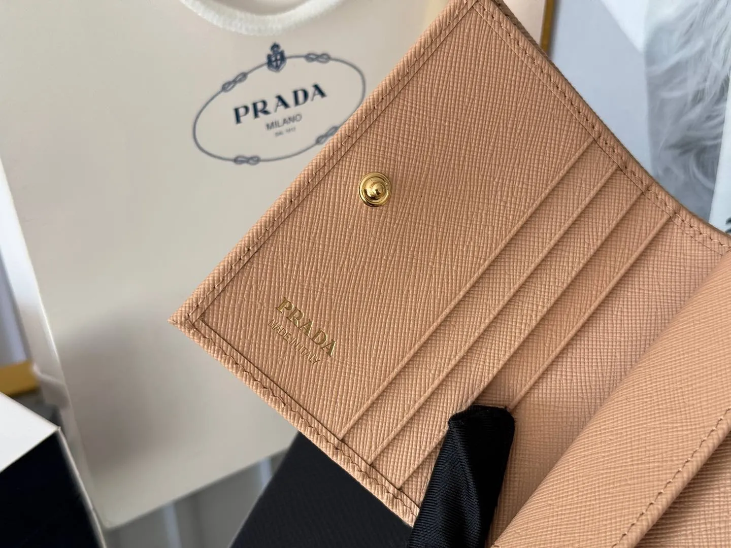 Prada women's two-fold short clip, with coin pocket and coin pocket. Model 1M0204, cross-grain cowhide. Size: 11.2x9.5cm. Simple and practical to enhance personal taste.