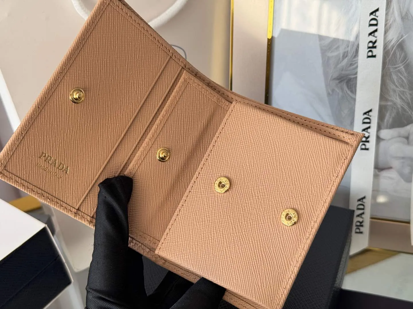Prada women's two-fold short clip, with coin pocket and coin pocket. Model 1M0204, cross-grain cowhide. Size: 11.2x9.5cm. Simple and practical to enhance personal taste.