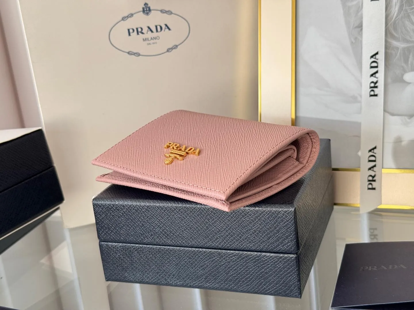 Prada women's two-fold short clip, with coin pocket and coin pocket. Model 1M0204, cross-grain cowhide. Size: 11.2x9.5cm. Simple and practical to enhance personal taste.