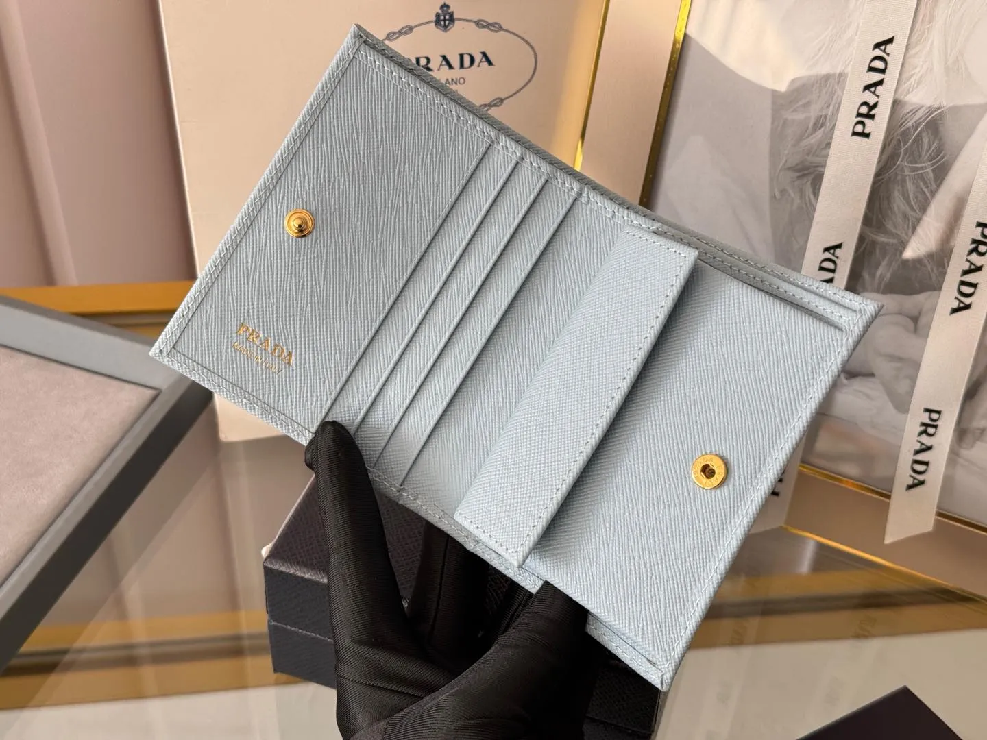 Prada women's two-fold short clip, with coin pocket and coin pocket. Model 1M0204, cross-grain cowhide. Size: 11.2x9.5cm. Simple and practical to enhance personal taste.