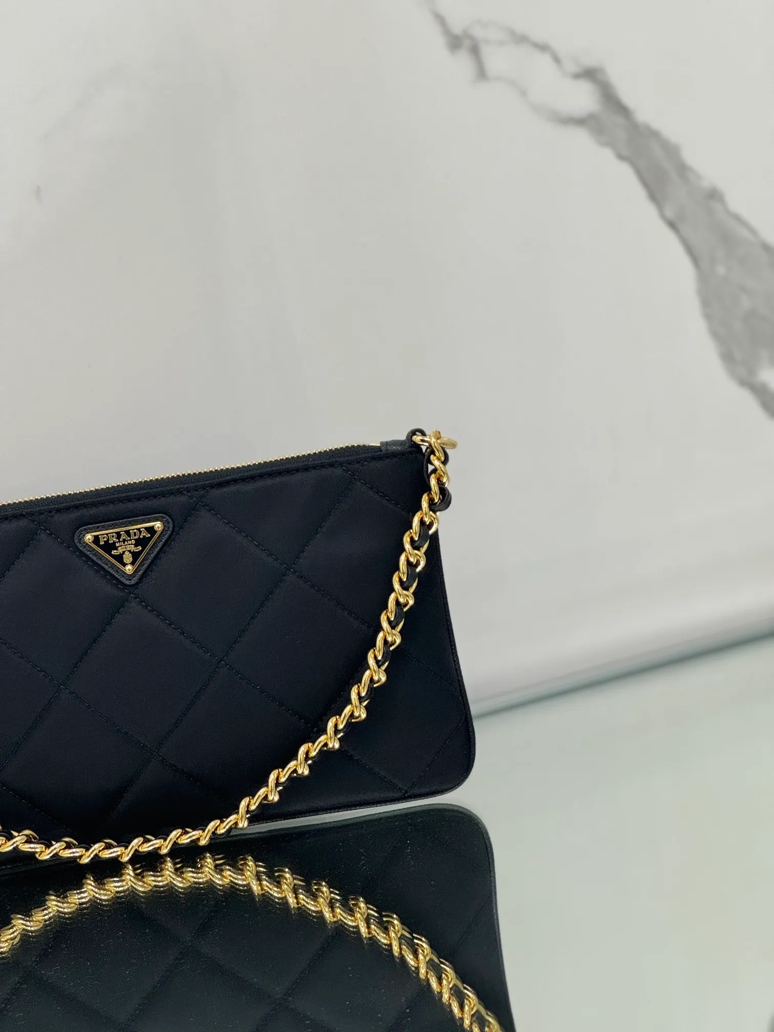 💰700🌟Chain Underarm Bag This clutch bag is made of regenerated nylon (Re-Nylon), which reflects the sustainable evolution of Prada's iconic fabric and adopts a simple and elegant design. Embodying the duality at the core of the brand, it cleverly blends modern and practical regenerated nylon with charming and refined details. It features chain handles, tonal stitching and the signature enameled triangle metal logo. Size: 24.5×14cm Style number: 1NI054
