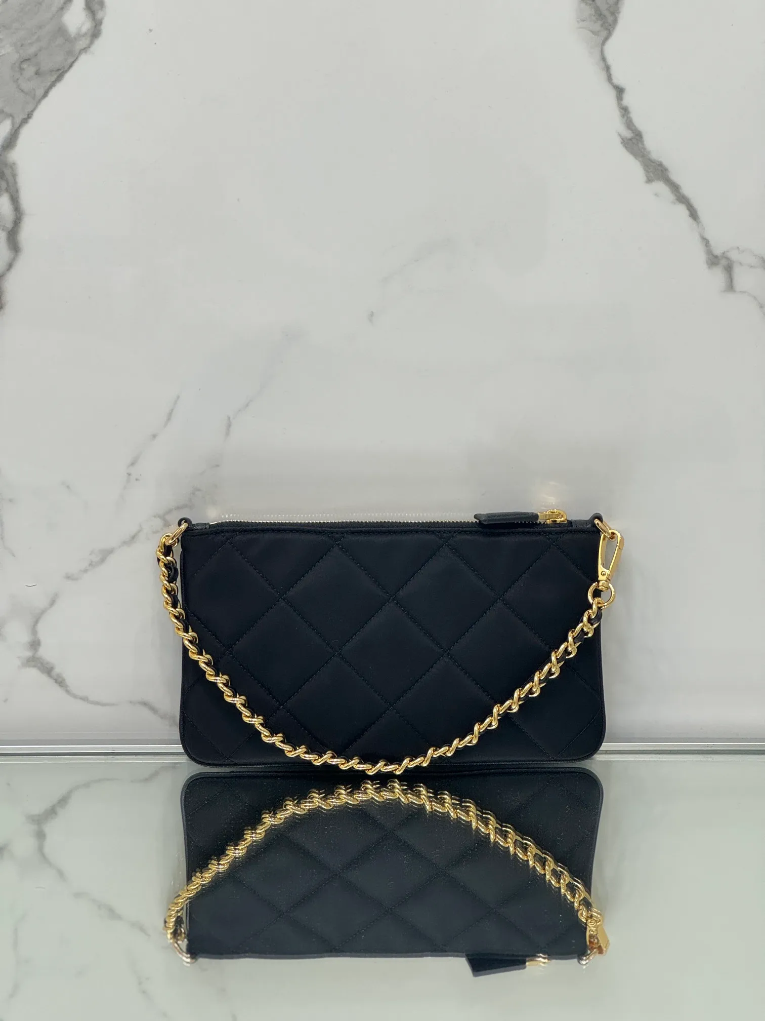 💰700🌟Chain Underarm Bag This clutch bag is made of regenerated nylon (Re-Nylon), which reflects the sustainable evolution of Prada's iconic fabric and adopts a simple and elegant design. Embodying the duality at the core of the brand, it cleverly blends modern and practical regenerated nylon with charming and refined details. It features chain handles, tonal stitching and the signature enameled triangle metal logo. Size: 24.5×14cm Style number: 1NI054