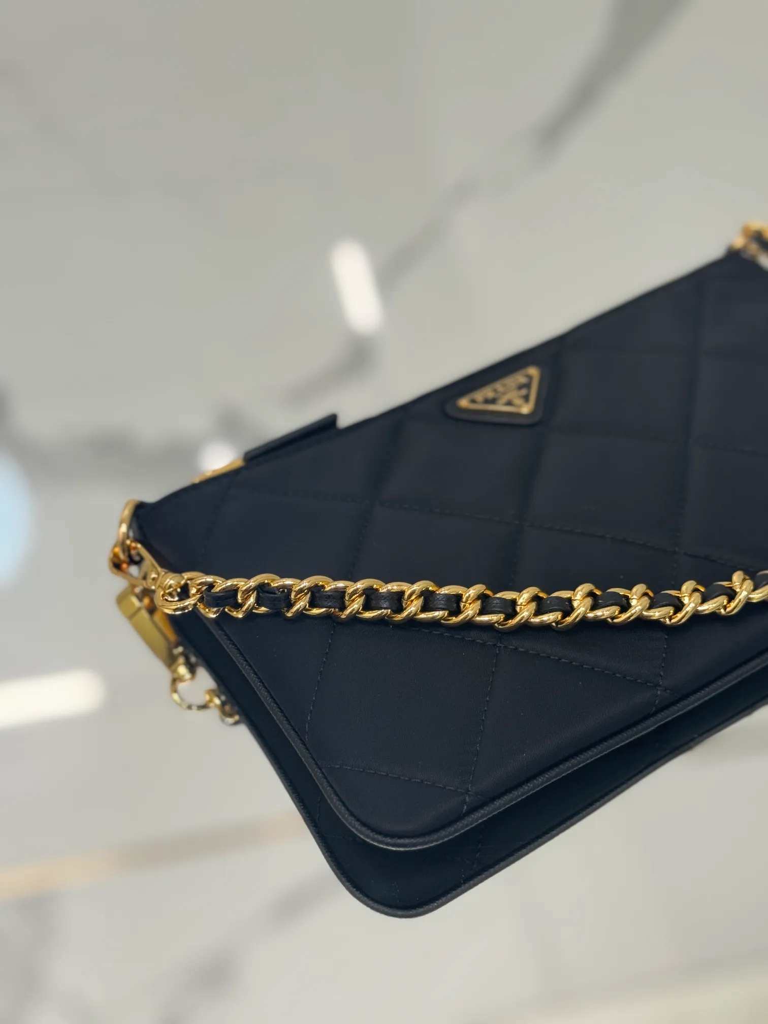 💰700🌟Chain Underarm Bag This clutch bag is made of regenerated nylon (Re-Nylon), which reflects the sustainable evolution of Prada's iconic fabric and adopts a simple and elegant design. Embodying the duality at the core of the brand, it cleverly blends modern and practical regenerated nylon with charming and refined details. It features chain handles, tonal stitching and the signature enameled triangle metal logo. Size: 24.5×14cm Style number: 1NI054