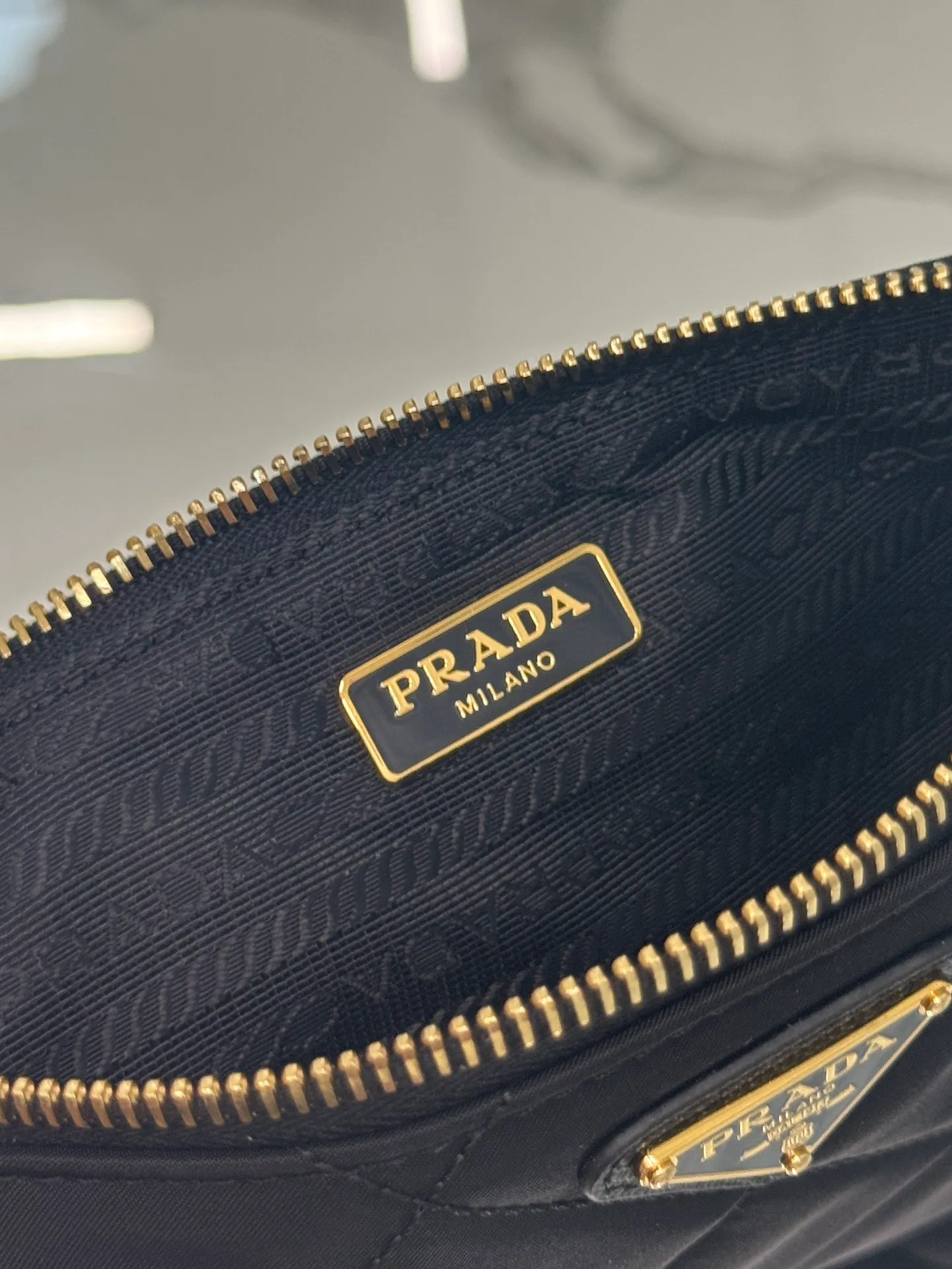 💰700🌟Chain Underarm Bag This clutch bag is made of regenerated nylon (Re-Nylon), which reflects the sustainable evolution of Prada's iconic fabric and adopts a simple and elegant design. Embodying the duality at the core of the brand, it cleverly blends modern and practical regenerated nylon with charming and refined details. It features chain handles, tonal stitching and the signature enameled triangle metal logo. Size: 24.5×14cm Style number: 1NI054