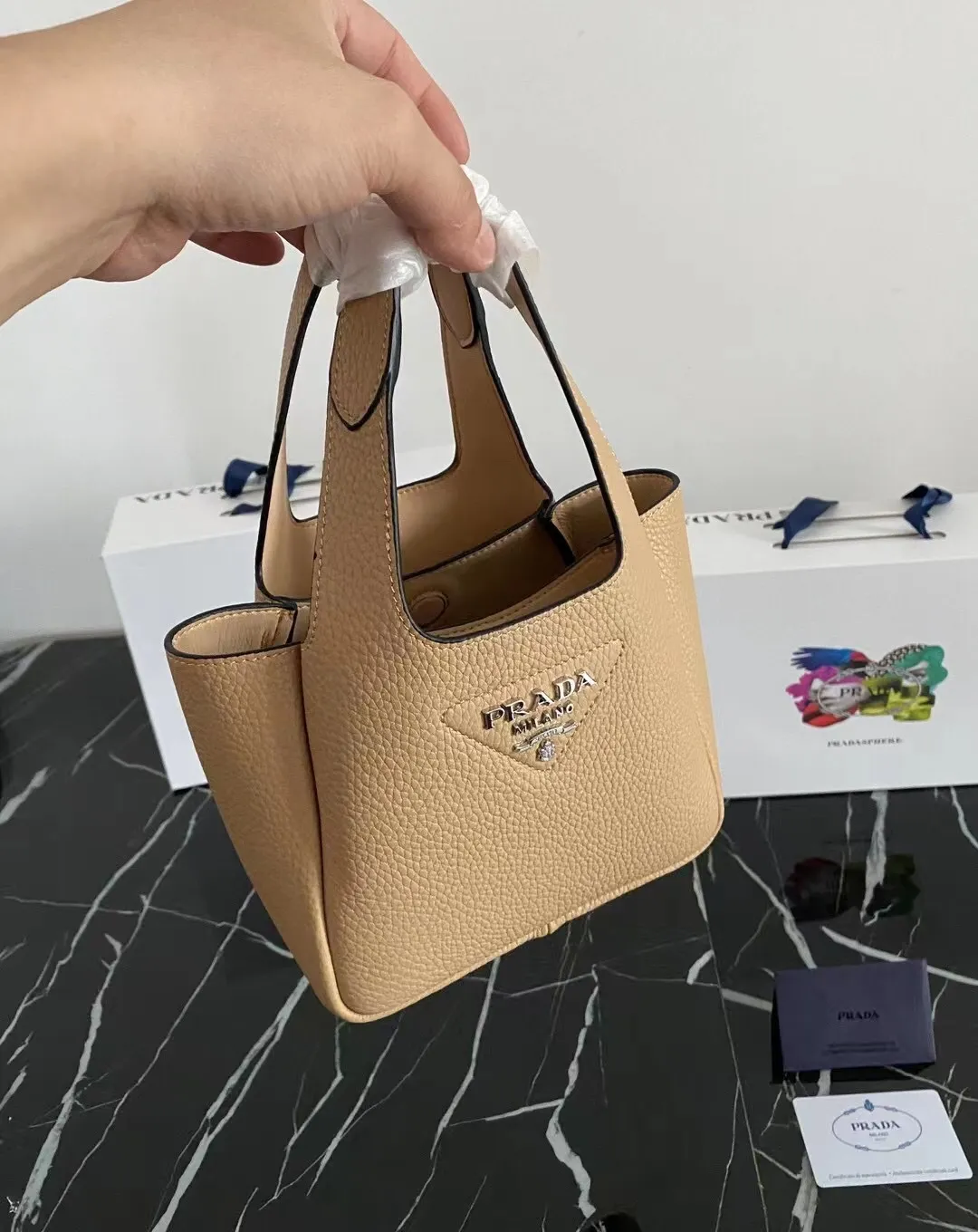 P1100¥ [Top original order] The latest 2022 vegetable basket tote bag mini model 1BA349 has arrived🎉🎉Soft and delicate pebbled calfskin tote bag, full leather inside and outside, equipped with double handles, decorated with silver metal logo, the overall body of the bag is very soft Lightweight, elegant and outstanding. The two side pockets not only meet the needs of exquisite storage but also add an elegant charm. It can be carried as a handbag or an armpit bag. It is a must-have handbag for fairies that perfectly combines classic heritage with the trend of the times. Size: 18︸15.5︸10CM!