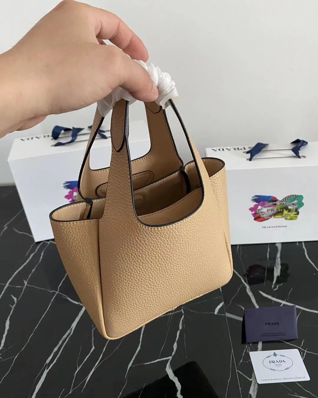 P1100¥ [Top original order] The latest 2022 vegetable basket tote bag mini model 1BA349 has arrived🎉🎉Soft and delicate pebbled calfskin tote bag, full leather inside and outside, equipped with double handles, decorated with silver metal logo, the overall body of the bag is very soft Lightweight, elegant and outstanding. The two side pockets not only meet the needs of exquisite storage but also add an elegant charm. It can be carried as a handbag or an armpit bag. It is a must-have handbag for fairies that perfectly combines classic heritage with the trend of the times. Size: 18︸15.5︸10CM!