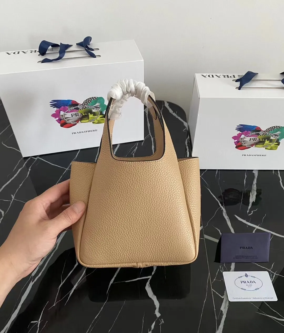 P1100¥ [Top original order] The latest 2022 vegetable basket tote bag mini model 1BA349 has arrived🎉🎉Soft and delicate pebbled calfskin tote bag, full leather inside and outside, equipped with double handles, decorated with silver metal logo, the overall body of the bag is very soft Lightweight, elegant and outstanding. The two side pockets not only meet the needs of exquisite storage but also add an elegant charm. It can be carried as a handbag or an armpit bag. It is a must-have handbag for fairies that perfectly combines classic heritage with the trend of the times. Size: 18︸15.5︸10CM!