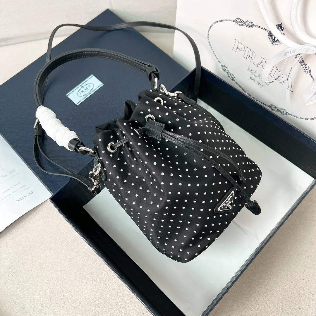 💰1140✨New product debut✨2025 new rivet decoration series bucket bag 1BE067 Imported recycled nylon fabric with rivet decoration Classic triangle logo Drawstring fastening design You can adjust the space at will Lightweight can be loaded and easy to match The randomness of different carrying methods and the ease of putting it anywhere Transform into a stylish girl in seconds🤩 Size：19.5/15.5/10