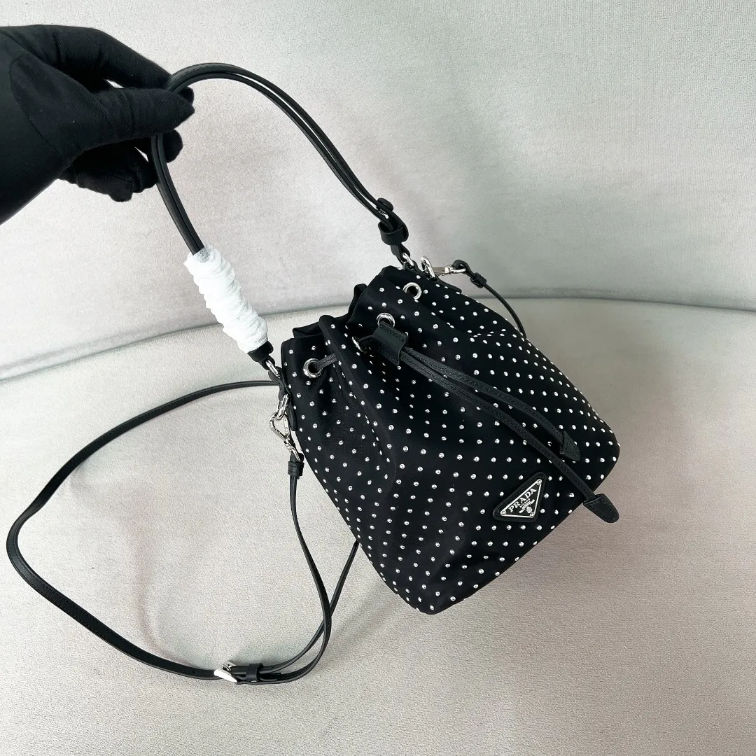 💰1140✨New product debut✨2025 new rivet decoration series bucket bag 1BE067 Imported recycled nylon fabric with rivet decoration Classic triangle logo Drawstring fastening design You can adjust the space at will Lightweight can be loaded and easy to match The randomness of different carrying methods and the ease of putting it anywhere Transform into a stylish girl in seconds🤩 Size：19.5/15.5/10