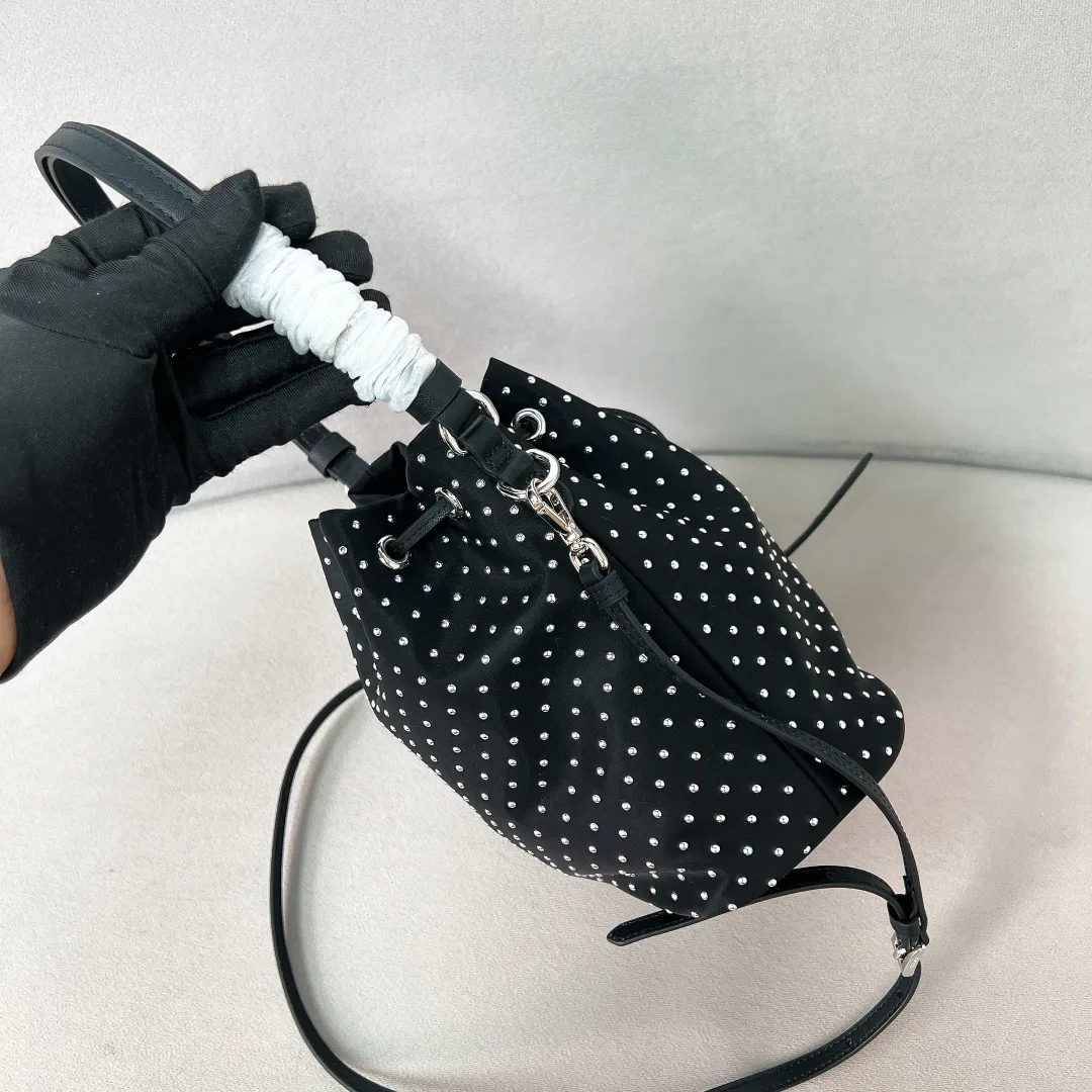 💰1140✨New product debut✨2025 new rivet decoration series bucket bag 1BE067 Imported recycled nylon fabric with rivet decoration Classic triangle logo Drawstring fastening design You can adjust the space at will Lightweight can be loaded and easy to match The randomness of different carrying methods and the ease of putting it anywhere Transform into a stylish girl in seconds🤩 Size：19.5/15.5/10