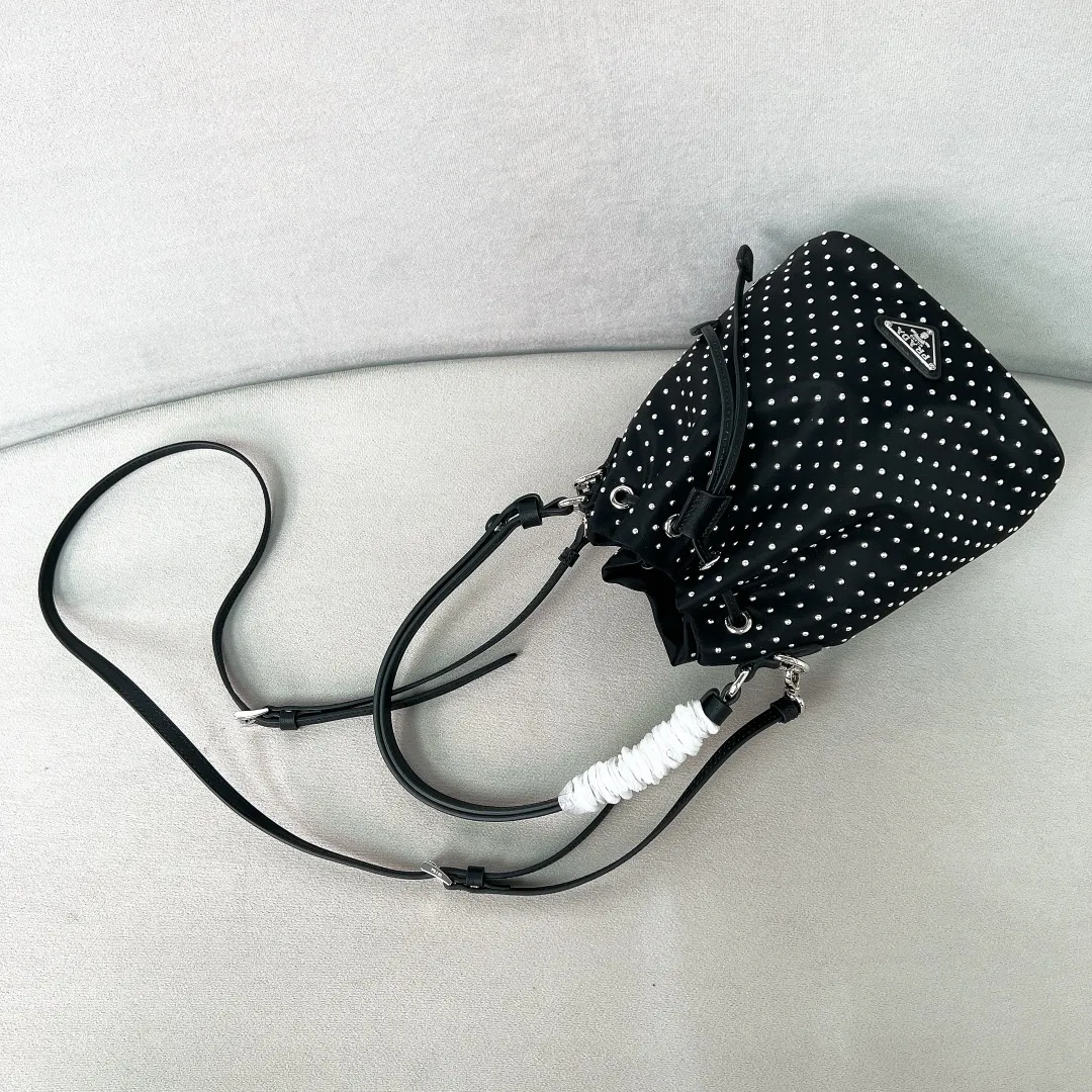 💰1140✨New product debut✨2025 new rivet decoration series bucket bag 1BE067 Imported recycled nylon fabric with rivet decoration Classic triangle logo Drawstring fastening design You can adjust the space at will Lightweight can be loaded and easy to match The randomness of different carrying methods and the ease of putting it anywhere Transform into a stylish girl in seconds🤩 Size：19.5/15.5/10