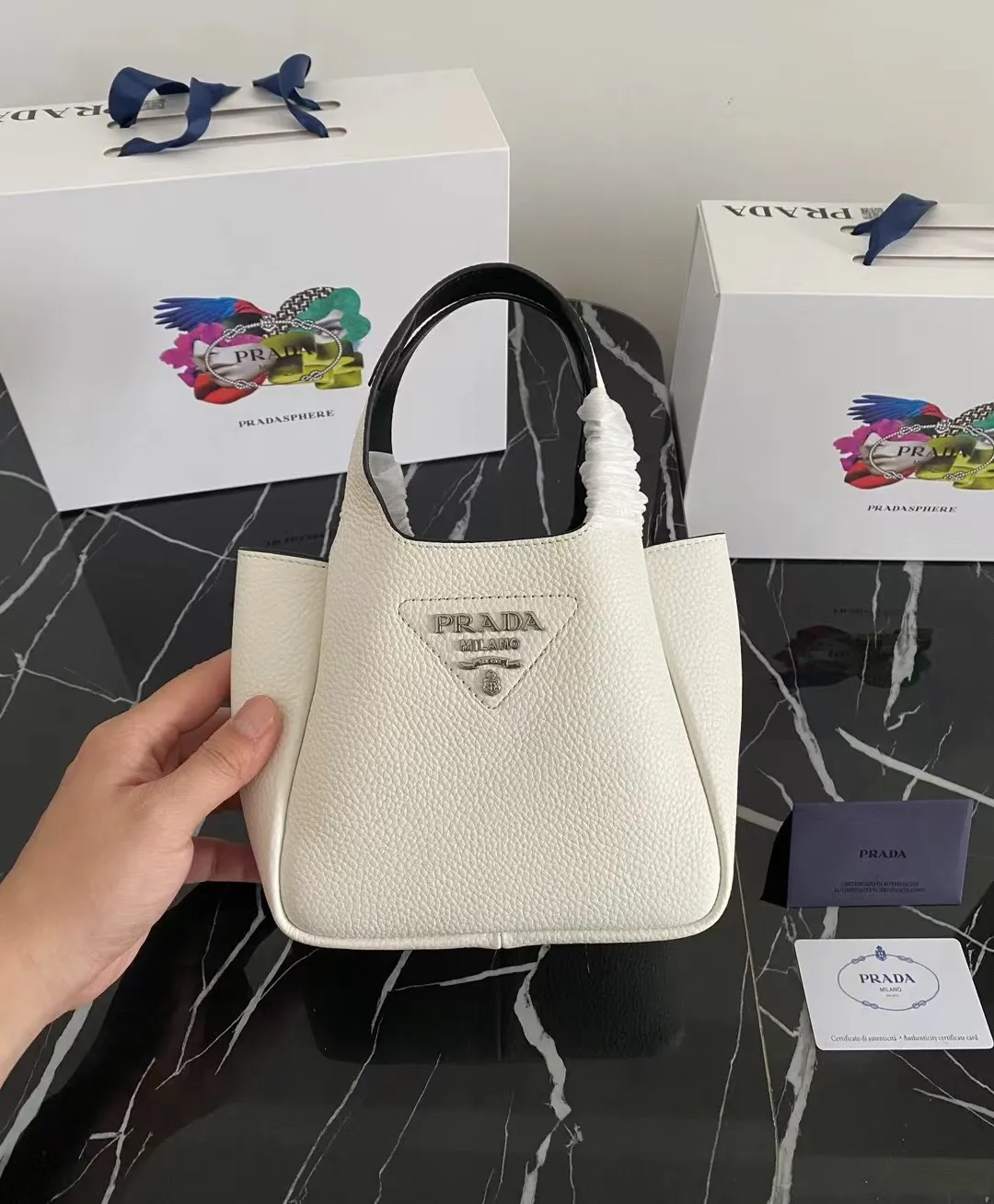 P1100¥ [Top original order] The latest 2022 vegetable basket tote bag mini model 1BA349 has arrived🎉🎉Soft and delicate pebbled calfskin tote bag, full leather inside and outside, equipped with double handles, decorated with silver metal logo, the overall body of the bag is very soft Lightweight, elegant and outstanding. The two side pockets not only meet the needs of exquisite storage but also add an elegant charm. It can be carried as a handbag or an armpit bag. It is a must-have handbag for fairies that perfectly combines classic heritage with the trend of the times. Size: 18︸15.5︸10CM!