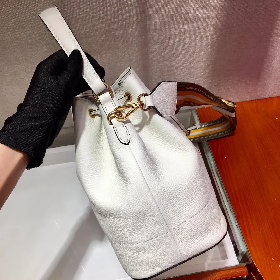 💰1660, P family has another popular bucket bag👏🏻👏🏻1BE018, the latest/most popular bucket bag🤙🤙Made of imported calfskin deerskin grain material, leather handle/2 replacement shoulder straps👏🏻👏🏻Detachable and adjustable colorful fabric shoulder straps, equipped with leather shoulder pads, metal lettering logo Decorated with a leather drawstring on the top, logo lining, there is a leather pocket inside, a large capacity and beautiful style🙋🏻🙋🏻, length 21x height 25x bottom 15cm.🤙🤙🤙💰💰💰