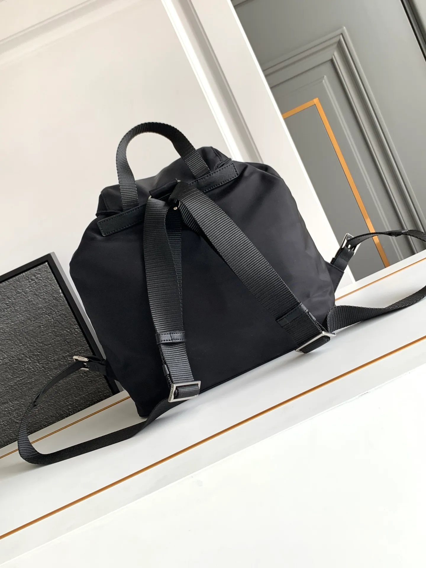 P640¥PR@DA 1BZ811 Nylon backpack is the most classic, best-selling and most versatile backpack of the P family. It is the first nylon bag designed by the chief founder himself. It is lightweight, rainproof, has a moderate capacity and is suitable for travel. It is matched with imported parachute fabric - waterproof and sunproof. Triangular enamel logo on the front, cross pattern cowhide trim. The overall style is fashionable and casual, yet stable and dignified. It has a large capacity to hold a kettle, iPad, mobile phone, books and documents. The drawstring inner bag + the two front zipper outer pockets meet the exquisite storage needs [Celebration]: 32*30*15cm black