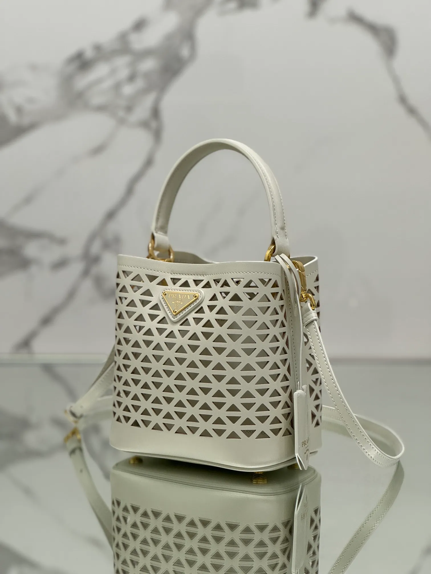 💰1640🌟Hollowout🐮Leather bucket bag The popular "elf" Saffiano perforated calfskin gives this P bucket bag a unique charm. The shape is not too soft and lacks spirit, nor is it too dull and lacks texture. The cute mini size adds a sense of fashion. It can be carried in hand, shoulder or crossbody. It is a handbag that perfectly integrates classic heritage and the trend of the times. Size: 18×17×10.5 cm Style number: 1BA217