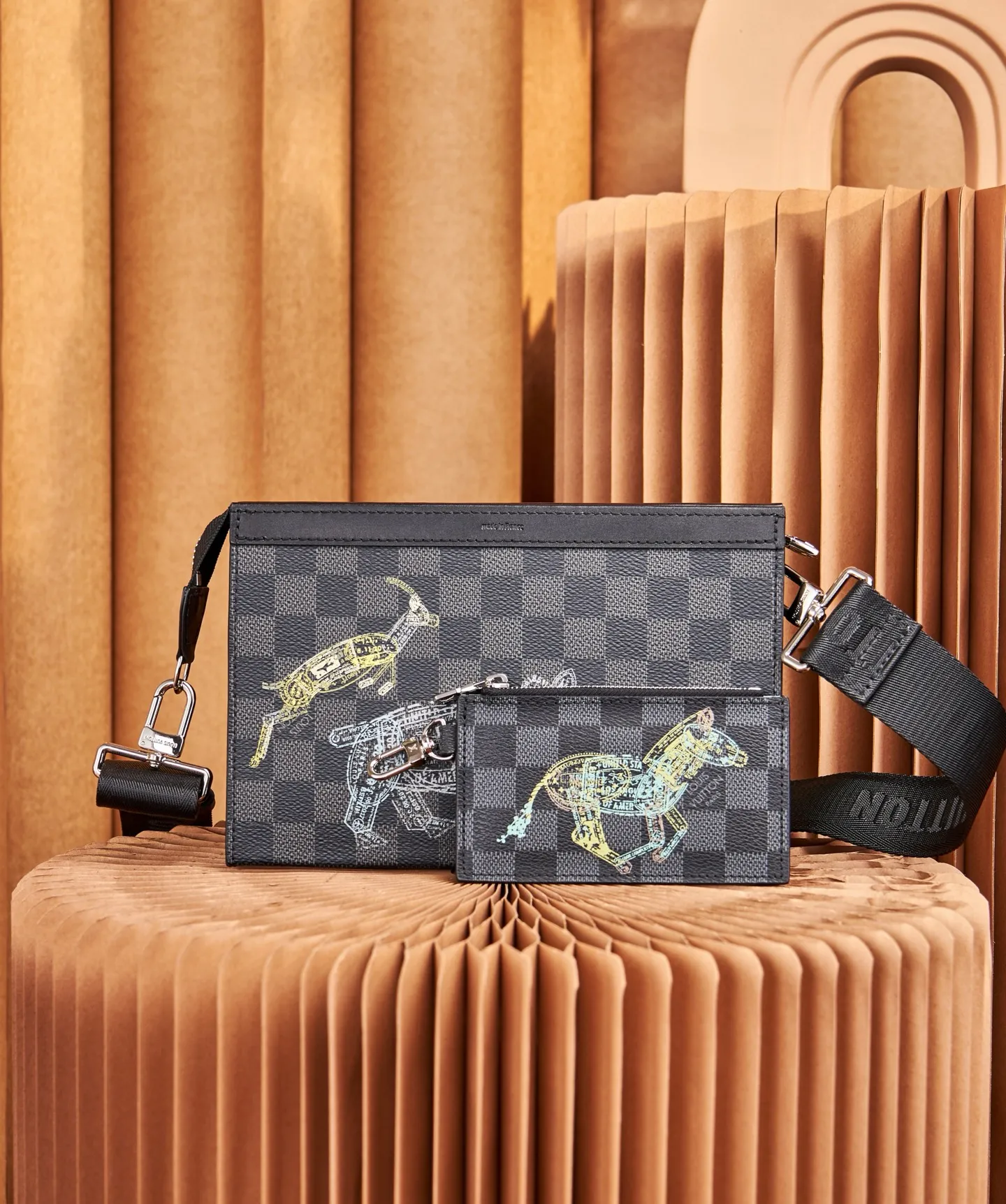 P¥640 [Top Original Order] N64608 This cross-body clutch and dual-use Gaston Wearable Wallet handbag is made of Damier Graphite canvas, with a customs seal-style pattern on the checkerboard surface to show the scene of charging elephants, tigers and ostriches. A removable card holder attached to the shoulder strap allows for touch-free payment. Dimensions: 22 x 14.5 x 4.5 cm