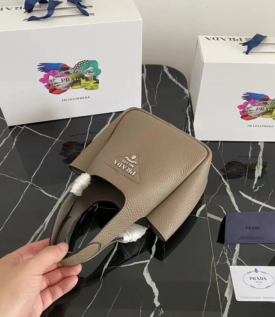 P1100¥ [Top original order] The latest 2022 vegetable basket tote bag mini model 1BA349 has arrived🎉🎉Soft and delicate pebbled calfskin tote bag, full leather inside and outside, equipped with double handles, decorated with silver metal logo, the overall body of the bag is very soft Lightweight, elegant and outstanding. The two side pockets not only meet the needs of exquisite storage but also add an elegant charm. It can be carried as a handbag or an armpit bag. It is a must-have handbag for fairies that perfectly combines classic heritage with the trend of the times. Size: 18︸15.5︸10CM!