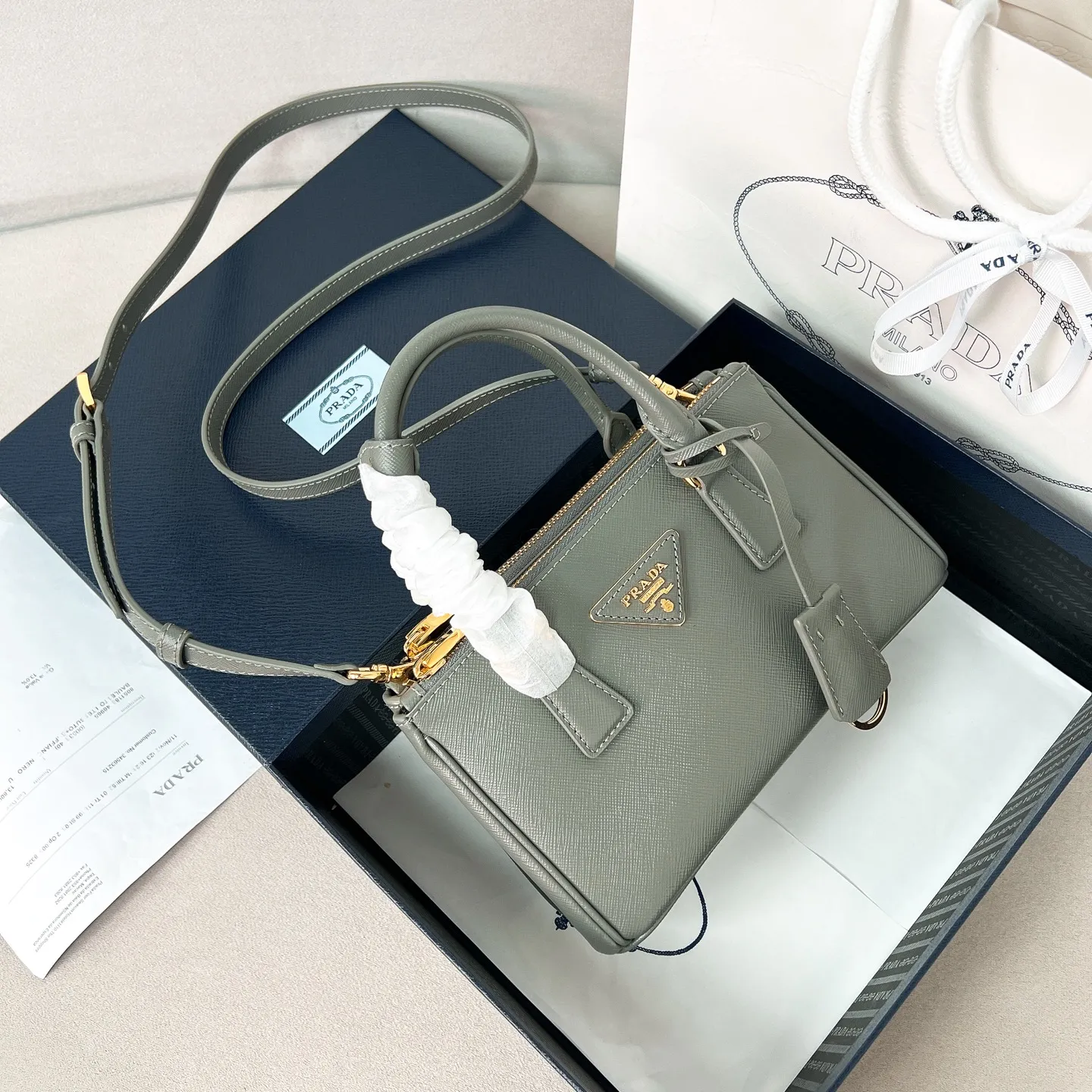 💰1700✨New product launch✨P classic Galleria Saffiano leather handbag - "Killer Bag" 2025 new product Mini No. 1BA916 People who understand fashion love killer bags. The bag should look like a killer bag. Carefully crafted with Saffiano cross pattern imported from Italy. Minimalist and capable bag shape with triangular metal lettering logo. Double zipper design, middle main bag with extra large capacity. Double handles and detachable shoulder straps make it It can be carried by hand or carried cross-body. It can be opened and closed with side snap buttons. The bag body changes to add elegance and elegance. It is small and exquisite, adding a playful and fashionable feel. Size 21*12.5*8.5 Gray