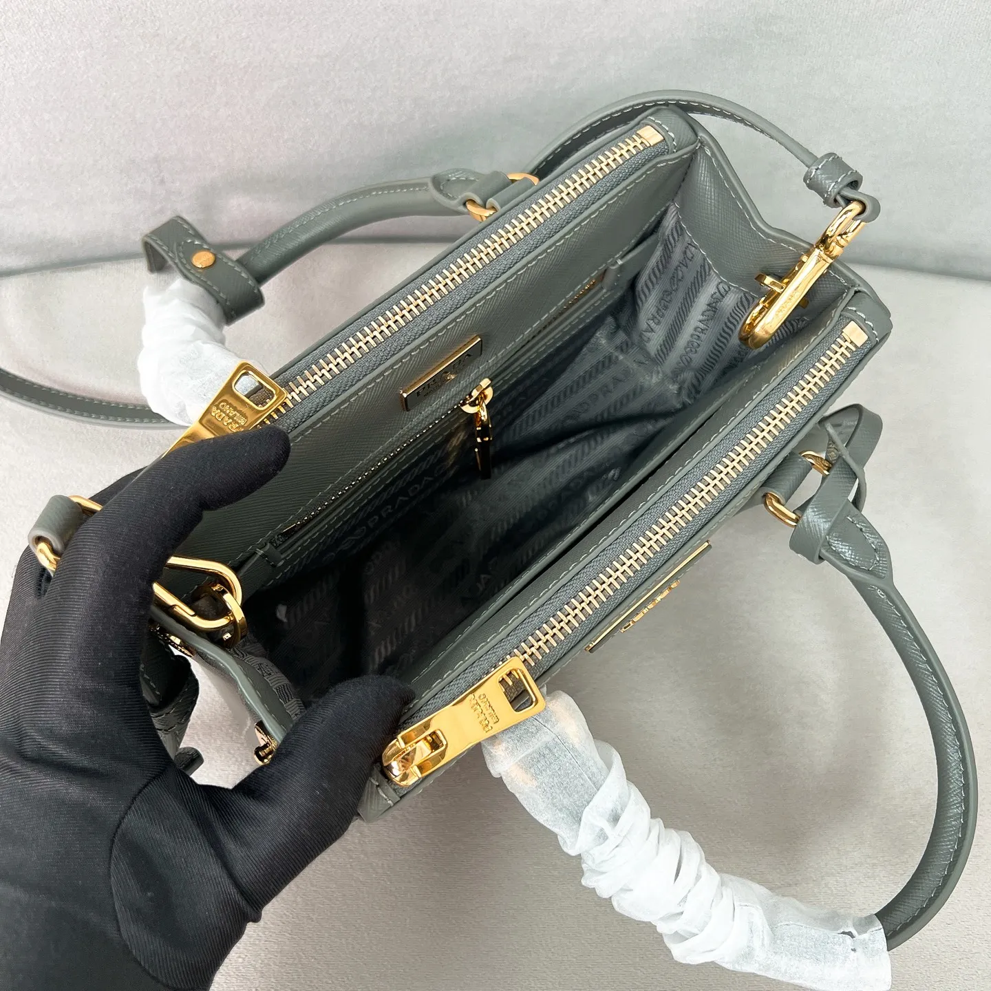 💰1700✨New product launch✨P classic Galleria Saffiano leather handbag - "Killer Bag" 2025 new product Mini No. 1BA916 People who understand fashion love killer bags. The bag should look like a killer bag. Carefully crafted with Saffiano cross pattern imported from Italy. Minimalist and capable bag shape with triangular metal lettering logo. Double zipper design, middle main bag with extra large capacity. Double handles and detachable shoulder straps make it It can be carried by hand or carried cross-body. It can be opened and closed with side snap buttons. The bag body changes to add elegance and elegance. It is small and exquisite, adding a playful and fashionable feel. Size 21*12.5*8.5 Gray