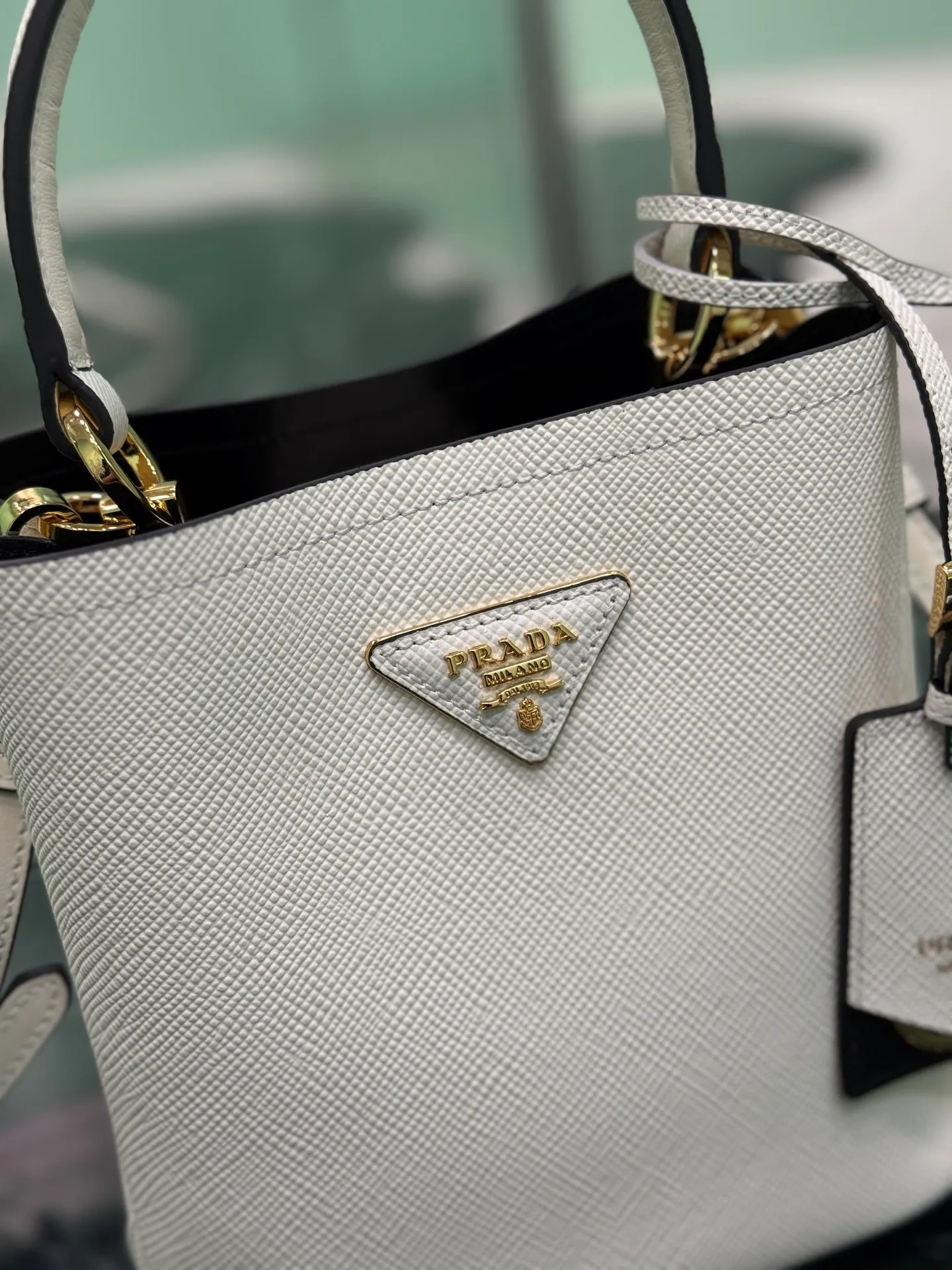 💰1700🌟 Classic bucket bag (new tag) Saffiano leather material Leather handles Detachable and adjustable leather shoulder strap Detachable leather name tag with metal logo Leather-covered central opening with magnetic buckle Saffiano leather triangle logo Contrast color nappa leather lining Size: 18×17×10.5cm Style number: 1BA217 (mini size)