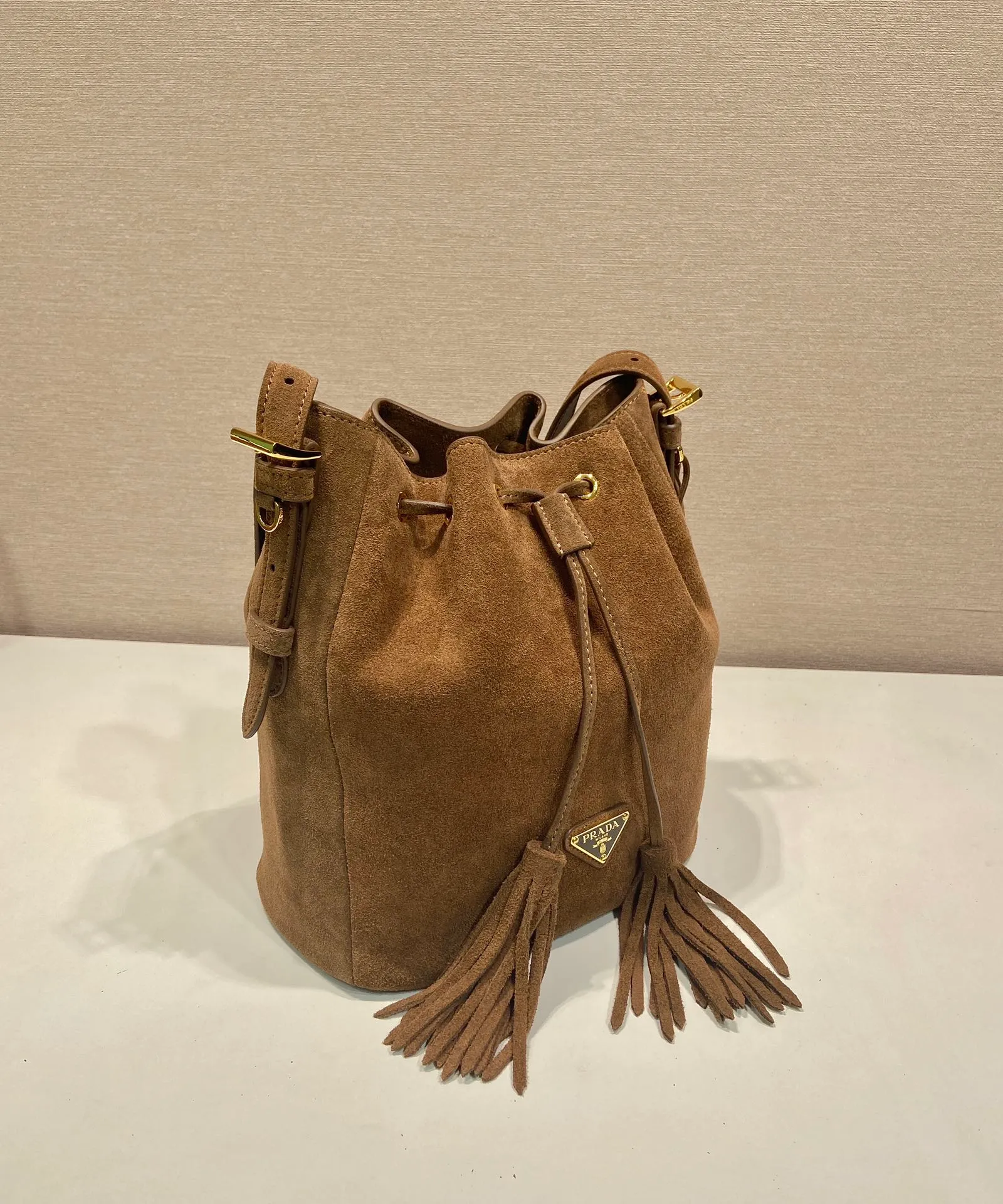 💰1400🎉New bucket bag🎉1BE079 suede leather🎉🎉 This flexible and easy-to-wear bucket bag has a minimalist design and is made of soft suede leather. The shoulder straps are adjustable, and the front panel is designed with 2 tassels. It has a large capacity space, and the upper body effect is fashionable. It is a must-have in winter and is worth owning👏👏👏 Length 25x Height 22x Bottom 13cm🎉🎉🎉👏👏👏