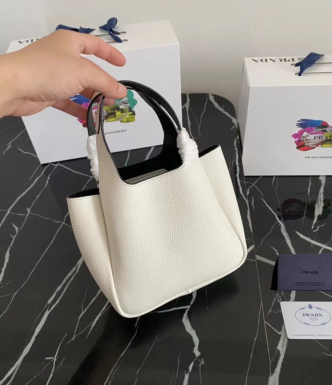 P1100¥ [Top original order] The latest 2022 vegetable basket tote bag mini model 1BA349 has arrived🎉🎉Soft and delicate pebbled calfskin tote bag, full leather inside and outside, equipped with double handles, decorated with silver metal logo, the overall body of the bag is very soft Lightweight, elegant and outstanding. The two side pockets not only meet the needs of exquisite storage but also add an elegant charm. It can be carried as a handbag or an armpit bag. It is a must-have handbag for fairies that perfectly combines classic heritage with the trend of the times. Size: 18︸15.5︸10CM!