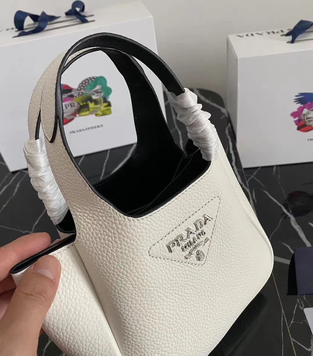 P1100¥ [Top original order] The latest 2022 vegetable basket tote bag mini model 1BA349 has arrived🎉🎉Soft and delicate pebbled calfskin tote bag, full leather inside and outside, equipped with double handles, decorated with silver metal logo, the overall body of the bag is very soft Lightweight, elegant and outstanding. The two side pockets not only meet the needs of exquisite storage but also add an elegant charm. It can be carried as a handbag or an armpit bag. It is a must-have handbag for fairies that perfectly combines classic heritage with the trend of the times. Size: 18︸15.5︸10CM!