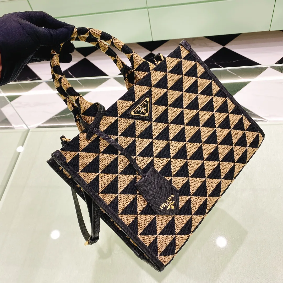 💰1560✨New product debut✨🌟New product, new series embroidered triangle plaid tote bag 1BA354 medium size. The new fashion favorite tote bag that is popular all over the world. The bag is embroidered with triangular geometric patterns all over the body and imported cross-grain cowhide trim. The overall bag is simple, elegant and luxurious in texture. The golden triangle logo on the front is added with Saffiano cowhide name plate. It is equipped with a detachable full leather shoulder strap. It has a large capacity and is full of matching points. A must-have tote bag for little fairies, size 22*9*28cm