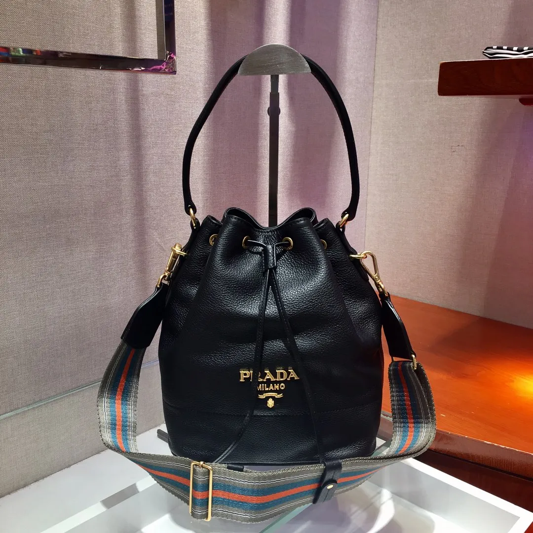 💰1660, P family has another popular bucket bag👏🏻👏🏻1BE018, the latest/most popular bucket bag🤙🤙Made of imported calfskin deerskin grain material, leather handle/2 replacement shoulder straps👏🏻👏🏻Detachable and adjustable colorful fabric shoulder straps, equipped with leather shoulder pads, metal lettering logo The top is decorated with a leather drawstring and is lined with a logo. There is a leather pocket inside, a large capacity and beautiful style🙋🏻🙋🏻, length 21x height 25x bottom 15cm.🤙