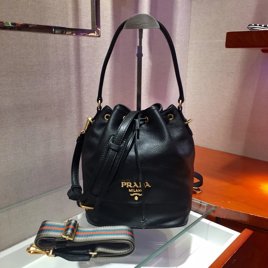 💰1660, P family has another popular bucket bag👏🏻👏🏻1BE018, the latest/most popular bucket bag🤙🤙Made of imported calfskin deerskin grain material, leather handle/2 replacement shoulder straps👏🏻👏🏻Detachable and adjustable colorful fabric shoulder straps, equipped with leather shoulder pads, metal lettering logo The top is decorated with a leather drawstring and is lined with a logo. There is a leather pocket inside, a large capacity and beautiful style🙋🏻🙋🏻, length 21x height 25x bottom 15cm.🤙