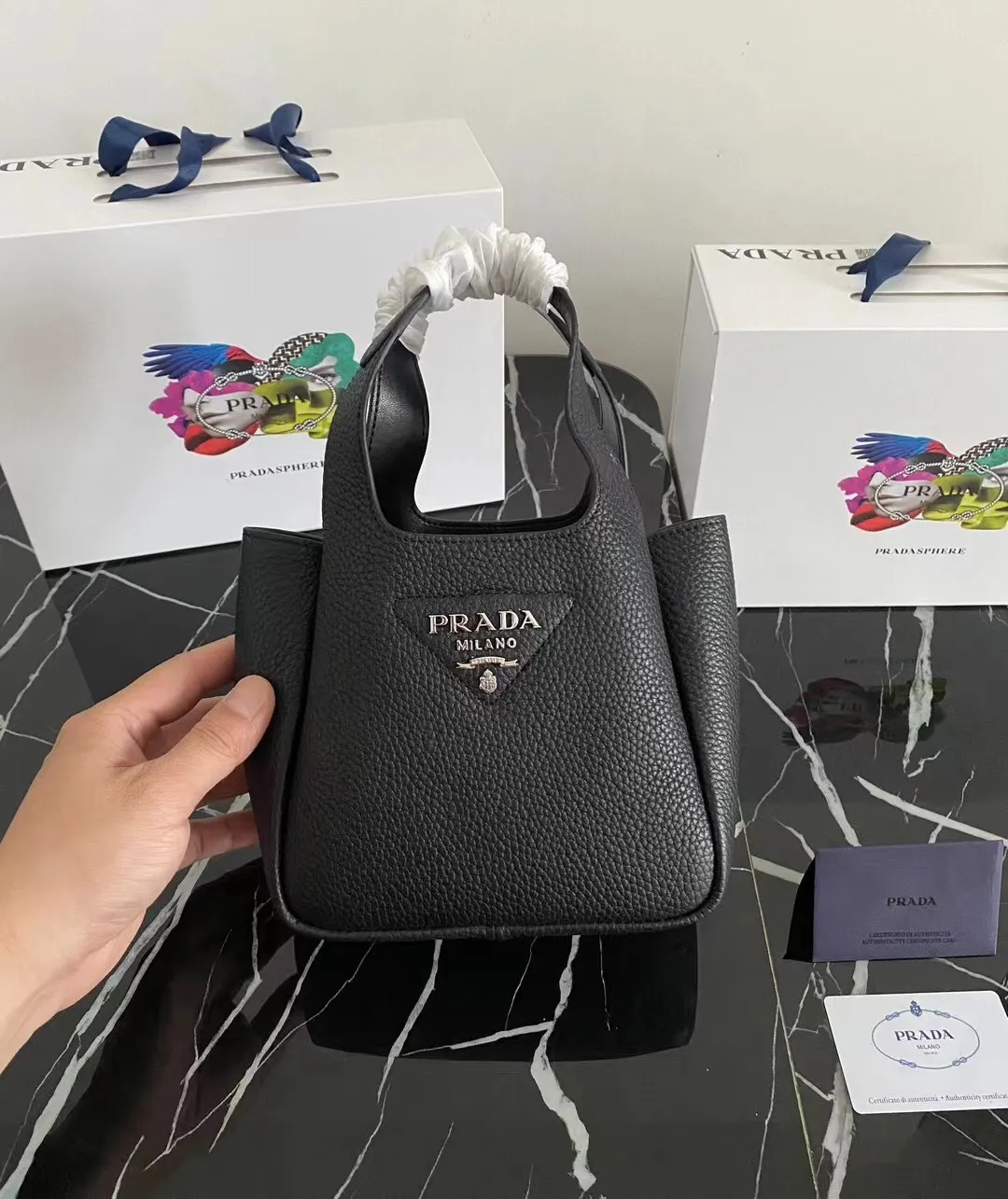 P1100¥ [Top original order] The latest 2022 vegetable basket tote bag mini model 1BA349 has arrived🎉🎉Soft and delicate pebbled calfskin tote bag, full leather inside and outside, equipped with double handles, decorated with silver metal logo, the overall body of the bag is very soft Lightweight, elegant and outstanding. The two side pockets not only meet the needs of exquisite storage but also add an elegant charm. It can be carried as a handbag or an armpit bag. It is a must-have handbag for fairies that perfectly combines classic heritage with the trend of the times. Size: 18︸15.5︸10CM!