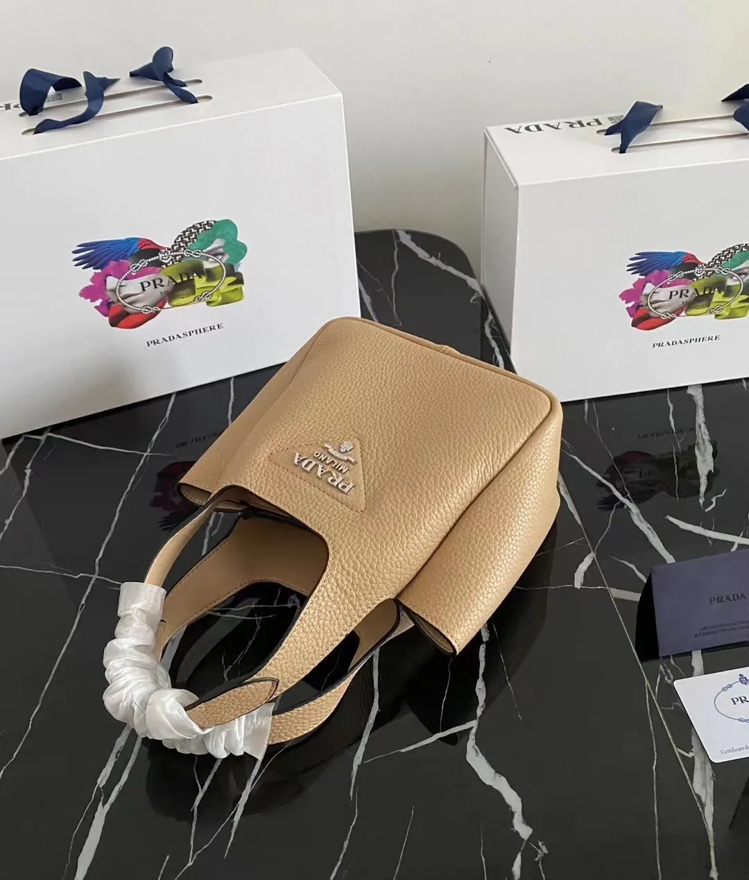 P1100¥ [Top original order] The latest 2022 vegetable basket tote bag mini model 1BA349 has arrived🎉🎉Soft and delicate pebbled calfskin tote bag, full leather inside and outside, equipped with double handles, decorated with silver metal logo, the overall body of the bag is very soft Lightweight, elegant and outstanding. The two side pockets not only meet the needs of exquisite storage but also add an elegant charm. It can be carried as a handbag or an armpit bag. It is a must-have handbag for fairies that perfectly combines classic heritage with the trend of the times. Size: 18︸15.5︸10CM!