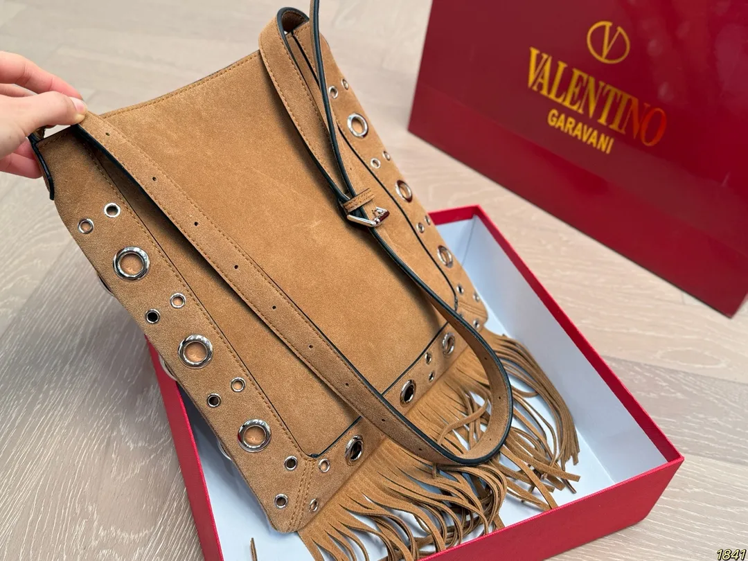 ¥330 with box Valentino tassel rivet handbag The tassel embellishment is super personalized! The V-shaped logo on the front is super classic and highly recognizable. The shoulder strap is adjustable, so it can be carried by hand or carried on the shoulder. It has a large capacity and can hold daily small items for commuting and traveling. The rivets and tassel design make the bag more layered, and it looks great with simple or retro styles. It is practical and fashionable, and can easily enhance the quality of your outfit! Size 29*30