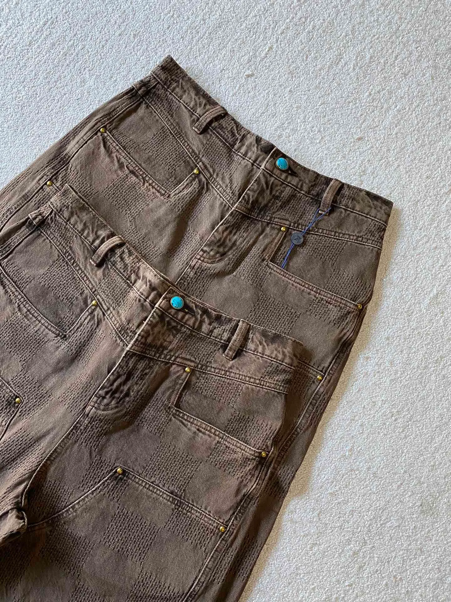 LV brown checkerboard denim straight trousers ⚠️Original purchase, 600, skateboard straight version, Marque L. Uuitton deposee logo integrated into 3D Damier jacquard, back Damier label, sand washed distressed, topstitch sewing, placket distressed hardware closure #Logo integrated into 3D Damier jacquard 3D Damier jacquard denim fabric is an innovative fabric that combines jacquard technology and the characteristics of denim cloth. The classic plaid pattern is combined with 3D jacquard technology to weave three-dimensional patterns on the fabric through a loom.  The fabric presents an exquisite plaid pattern in appearance, and the pattern is made three-dimensional and layered through jacquard technology. At the same time, it retains the original tough, wear-resistant and durable properties of denim, making the clothes more durable.  # Sandwashed, Faded and Distressed Effect Sandwashed, faded and distressed denim fabric is a specially treated denim fabric that exhibits a whitened and distressed effect. This fabric uses a sand-washing process and special dyeing technology to create a natural wear and fading effect on the denim after washing, making it look more vintage and historical.  #skateboard straight jeans version Skateboard jeans are usually designed to be looser to accommodate the large movements and squatting postures during skateboarding. Jeans have a straight shape and a consistent width from hip to hem. Suitable for all body types, these straight-leg skateboard pants are designed with comfort and freedom in mind for skateboarding.