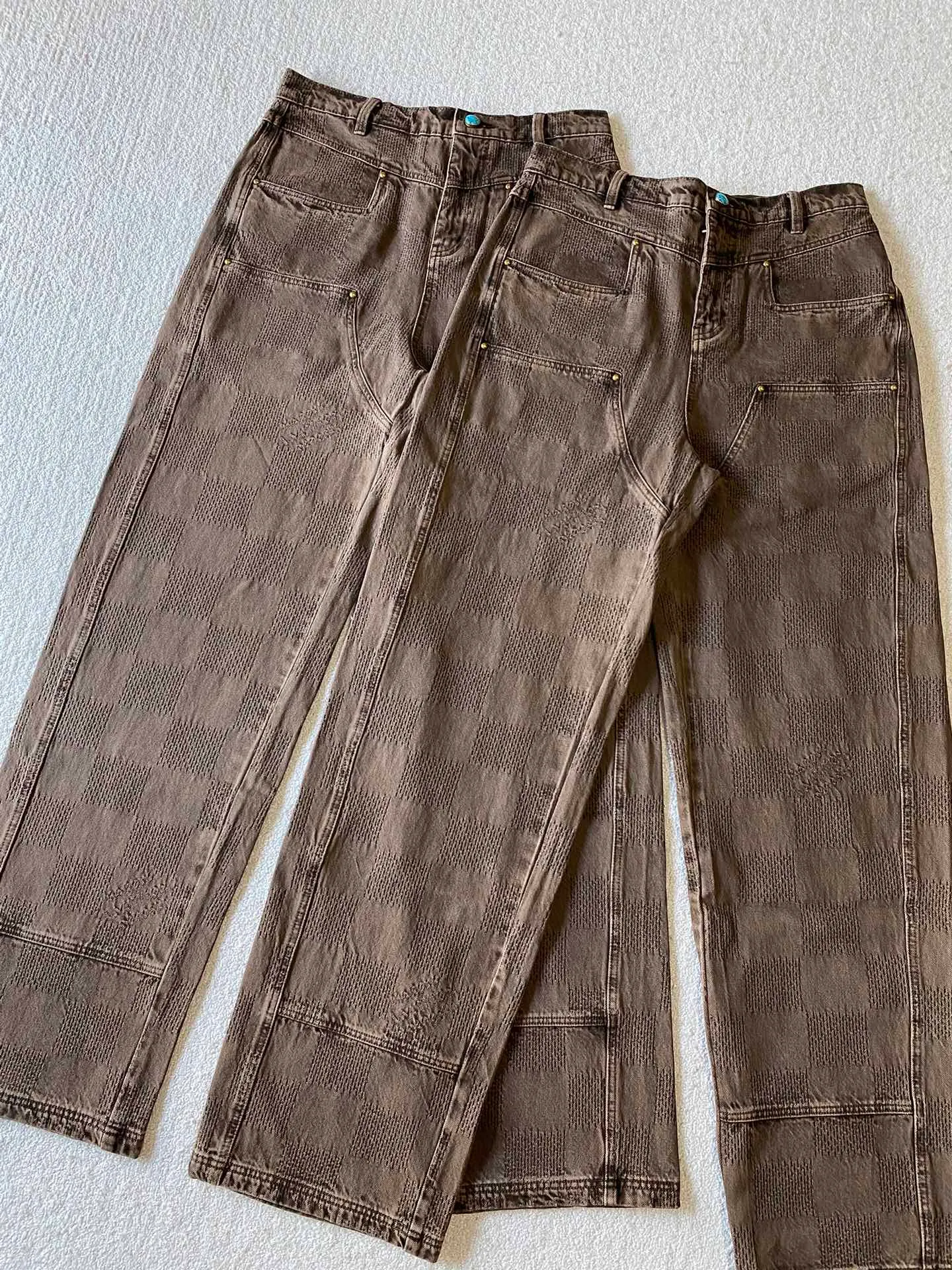 LV brown checkerboard denim straight trousers ⚠️Original purchase, 600, skateboard straight version, Marque L. Uuitton deposee logo integrated into 3D Damier jacquard, back Damier label, sand washed distressed, topstitch sewing, placket distressed hardware closure #Logo integrated into 3D Damier jacquard 3D Damier jacquard denim fabric is an innovative fabric that combines jacquard technology and the characteristics of denim cloth. The classic plaid pattern is combined with 3D jacquard technology to weave three-dimensional patterns on the fabric through a loom.  The fabric presents an exquisite plaid pattern in appearance, and the pattern is made three-dimensional and layered through jacquard technology. At the same time, it retains the original tough, wear-resistant and durable properties of denim, making the clothes more durable.  # Sandwashed, Faded and Distressed Effect Sandwashed, faded and distressed denim fabric is a specially treated denim fabric that exhibits a whitened and distressed effect. This fabric uses a sand-washing process and special dyeing technology to create a natural wear and fading effect on the denim after washing, making it look more vintage and historical.  #skateboard straight jeans version Skateboard jeans are usually designed to be looser to accommodate the large movements and squatting postures during skateboarding. Jeans have a straight shape and a consistent width from hip to hem. Suitable for all body types, these straight-leg skateboard pants are designed with comfort and freedom in mind for skateboarding.
