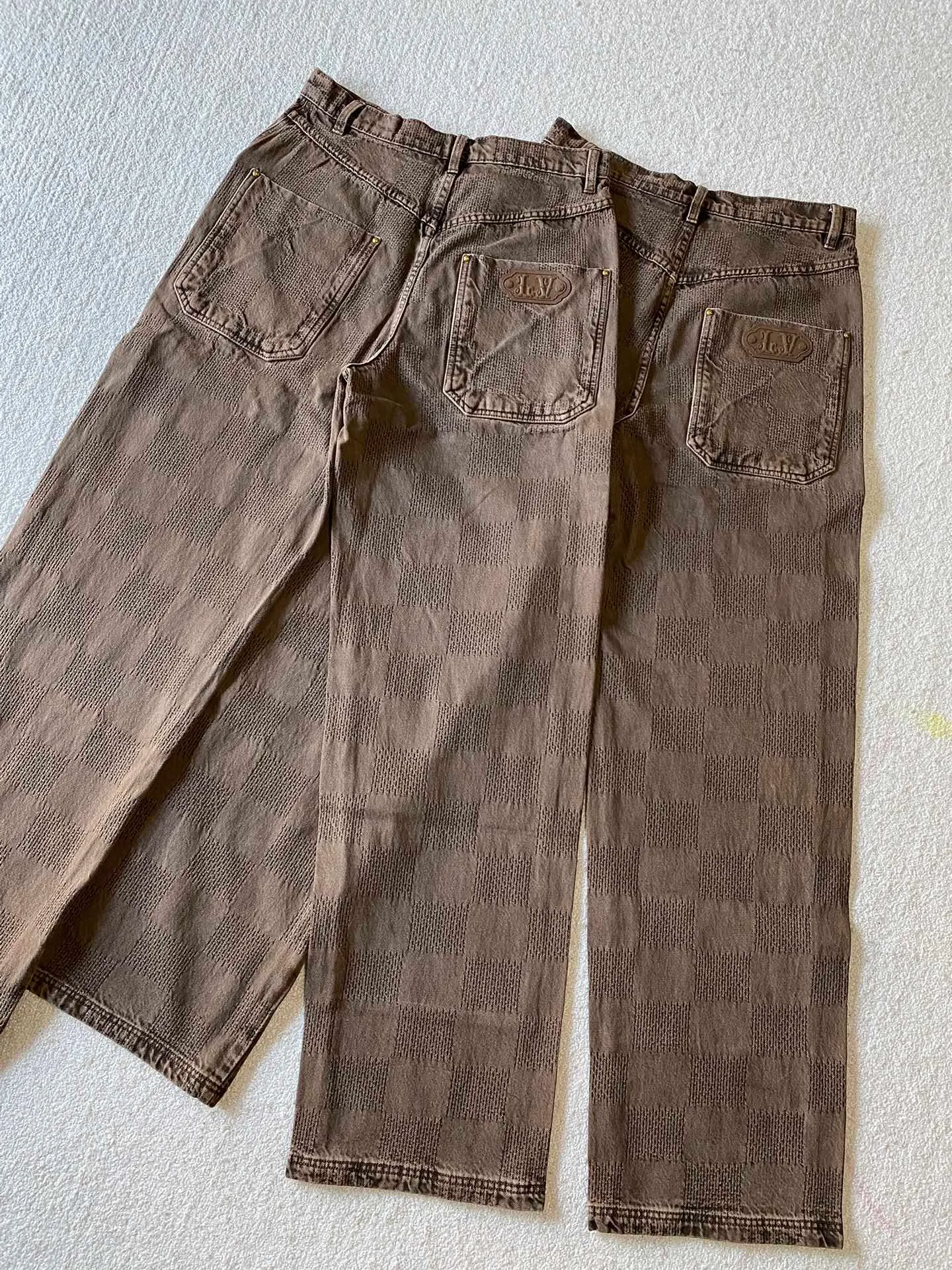 LV brown checkerboard denim straight trousers ⚠️Original purchase, 600, skateboard straight version, Marque L. Uuitton deposee logo integrated into 3D Damier jacquard, back Damier label, sand washed distressed, topstitch sewing, placket distressed hardware closure #Logo integrated into 3D Damier jacquard 3D Damier jacquard denim fabric is an innovative fabric that combines jacquard technology and the characteristics of denim cloth. The classic plaid pattern is combined with 3D jacquard technology to weave three-dimensional patterns on the fabric through a loom.  The fabric presents an exquisite plaid pattern in appearance, and the pattern is made three-dimensional and layered through jacquard technology. At the same time, it retains the original tough, wear-resistant and durable properties of denim, making the clothes more durable.  # Sandwashed, Faded and Distressed Effect Sandwashed, faded and distressed denim fabric is a specially treated denim fabric that exhibits a whitened and distressed effect. This fabric uses a sand-washing process and special dyeing technology to create a natural wear and fading effect on the denim after washing, making it look more vintage and historical.  #skateboard straight jeans version Skateboard jeans are usually designed to be looser to accommodate the large movements and squatting postures during skateboarding. Jeans have a straight shape and a consistent width from hip to hem. Suitable for all body types, these straight-leg skateboard pants are designed with comfort and freedom in mind for skateboarding.