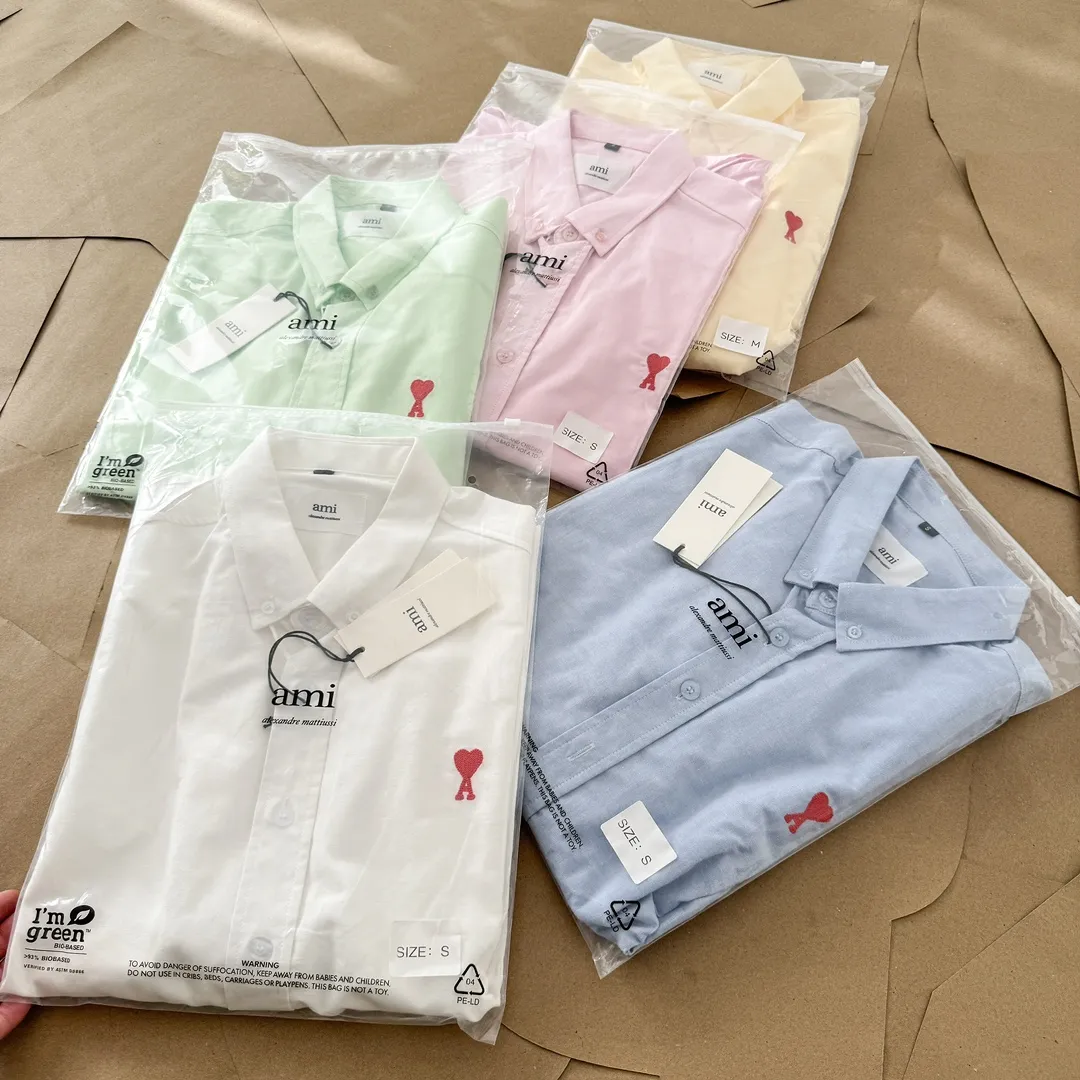 Ami Paris Oxford cotton button-down corner collar casual short-sleeved shirt - small love silhouette style - same style for men and women. Red small love letter embroidery decoration, fashionable and versatile short-sleeved shirt! The counter sells famous French affordable luxury fashion brands at the same time. The classic elements of the brand are popular among celebrities. The basic simple design and fashionable style are must-have couple shirts for men and women!  Made of custom-woven 100% Oxford cloth pure cotton, it feels soft and delicate, has excellent moisture absorption and perspiration performance, and is very comfortable and skin-friendly when worn next to the skin! The chest of the shirt is decorated with the classic love letter A logo embroidery. The top-notch embroidery technology is tight, full and full of details, and is cleverly embellished with bright red. It carries all the eye-catching points. It follows the consistent minimalist French attitude. The fabric is soft and comfortable, suitable for any versatile casual shirt couple!  Color: Blue White Yellow Green Pink Size: S-XL Size: Size Length Bust Shoulder Width Sleeve Length S 73.5 68 56 26.5 M 75.5 70 57 27 L 77.5 72 58 27.5 XL 79.5 74 59 28