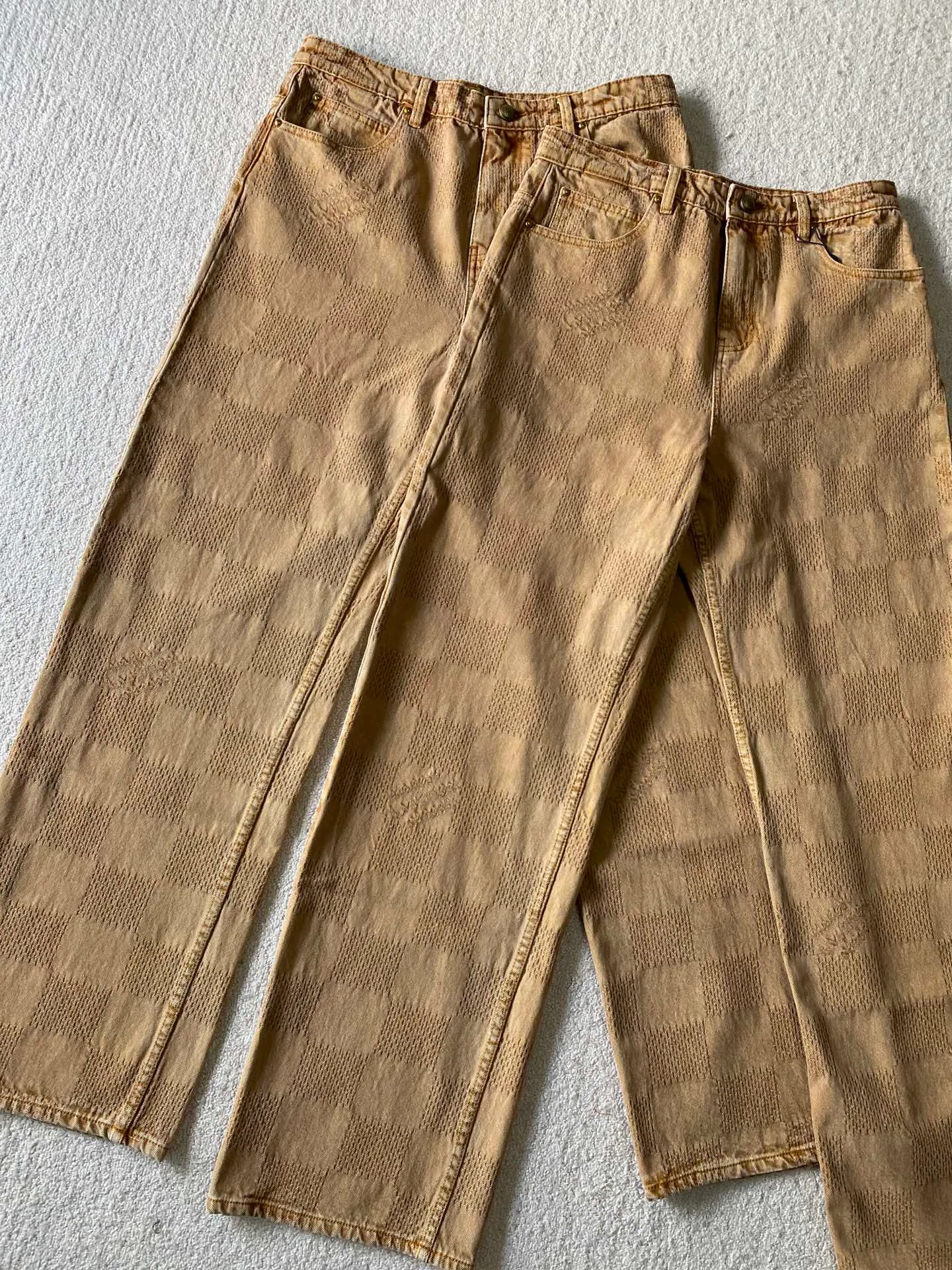 LV saddle checkerboard denim suit · trousers ⚠️Original purchase, 600, skateboard straight version, Marque L. Uuitton deposee logo integrated into 3D Damier jacquard, back Damier label, sand washed distressed, topstitch sewing, placket distressed hardware closure #Logo integrated into 3D Damier jacquard 3D Damier jacquard denim fabric is an innovative fabric that combines jacquard technology and the characteristics of denim cloth. The classic plaid pattern is combined with 3D jacquard technology to weave three-dimensional patterns on the fabric through a loom.  The fabric presents an exquisite plaid pattern in appearance, and the pattern is made three-dimensional and layered through jacquard technology. At the same time, it retains the original tough, wear-resistant and durable properties of denim, making the clothes more durable.  #Grey cloth retro coloring process is a process that uses a specific process to make the originally white denim show a retro, worn-out special color effect. Clean the white denim fabric to remove surface impurities and residues. Through specific processing methods, the fabric can maintain stable dimensions during subsequent processing.  Choose the appropriate natural dye for the desired distressing effect on the plate. The dye is evenly applied to the fabric, giving it a gradient coloring effect. After dyeing is completed, necessary cleaning and color fixing treatments are required to ensure color stability and durability.  # Sandwashed, Faded and Distressed Effect Sandwashed, faded and distressed denim fabric is a specially treated denim fabric that exhibits a whitened and distressed effect. This fabric uses a sand-washing process and special dyeing technology to create a natural wear and fading effect on the denim after washing, making it look more vintage and historical.  #skateboard straight jeans version Skateboard jeans are usually designed to be looser to accommodate the large movements and squatting postures during skateboarding. Jeans have a straight shape and a consistent width from hip to hem. Suitable for all body types, these straight-leg skateboard pants are designed with comfort and freedom in mind for skateboarding.