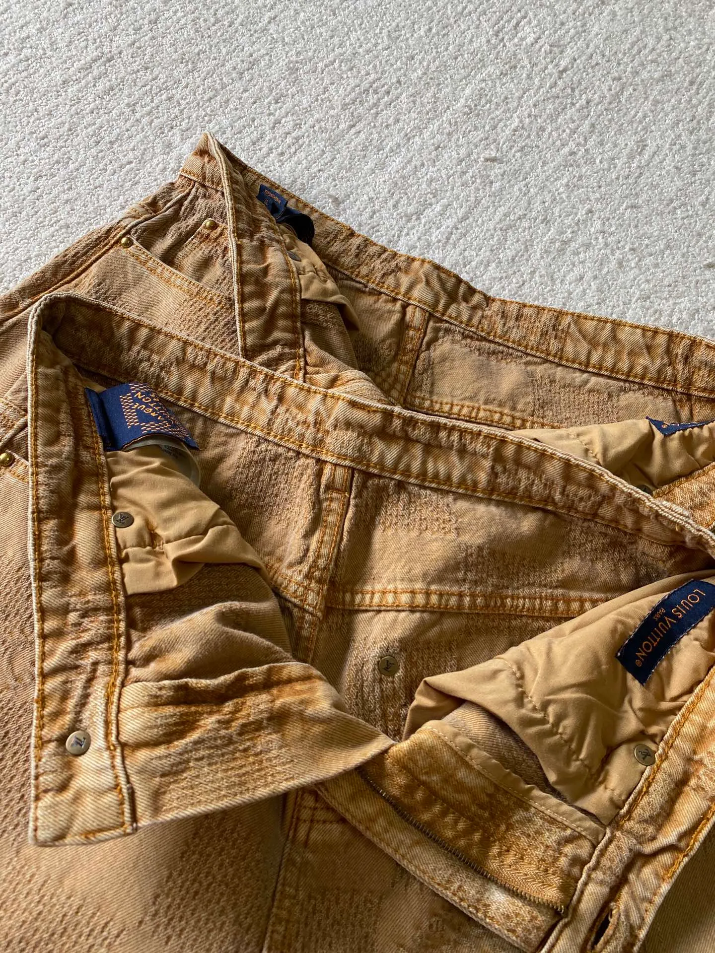 LV saddle checkerboard denim suit · trousers ⚠️Original purchase, 600, skateboard straight version, Marque L. Uuitton deposee logo integrated into 3D Damier jacquard, back Damier label, sand washed distressed, topstitch sewing, placket distressed hardware closure #Logo integrated into 3D Damier jacquard 3D Damier jacquard denim fabric is an innovative fabric that combines jacquard technology and the characteristics of denim cloth. The classic plaid pattern is combined with 3D jacquard technology to weave three-dimensional patterns on the fabric through a loom.  The fabric presents an exquisite plaid pattern in appearance, and the pattern is made three-dimensional and layered through jacquard technology. At the same time, it retains the original tough, wear-resistant and durable properties of denim, making the clothes more durable.  #Grey cloth retro coloring process is a process that uses a specific process to make the originally white denim show a retro, worn-out special color effect. Clean the white denim fabric to remove surface impurities and residues. Through specific processing methods, the fabric can maintain stable dimensions during subsequent processing.  Choose the appropriate natural dye for the desired distressing effect on the plate. The dye is evenly applied to the fabric, giving it a gradient coloring effect. After dyeing is completed, necessary cleaning and color fixing treatments are required to ensure color stability and durability.  # Sandwashed, Faded and Distressed Effect Sandwashed, faded and distressed denim fabric is a specially treated denim fabric that exhibits a whitened and distressed effect. This fabric uses a sand-washing process and special dyeing technology to create a natural wear and fading effect on the denim after washing, making it look more vintage and historical.  #skateboard straight jeans version Skateboard jeans are usually designed to be looser to accommodate the large movements and squatting postures during skateboarding. Jeans have a straight shape and a consistent width from hip to hem. Suitable for all body types, these straight-leg skateboard pants are designed with comfort and freedom in mind for skateboarding.