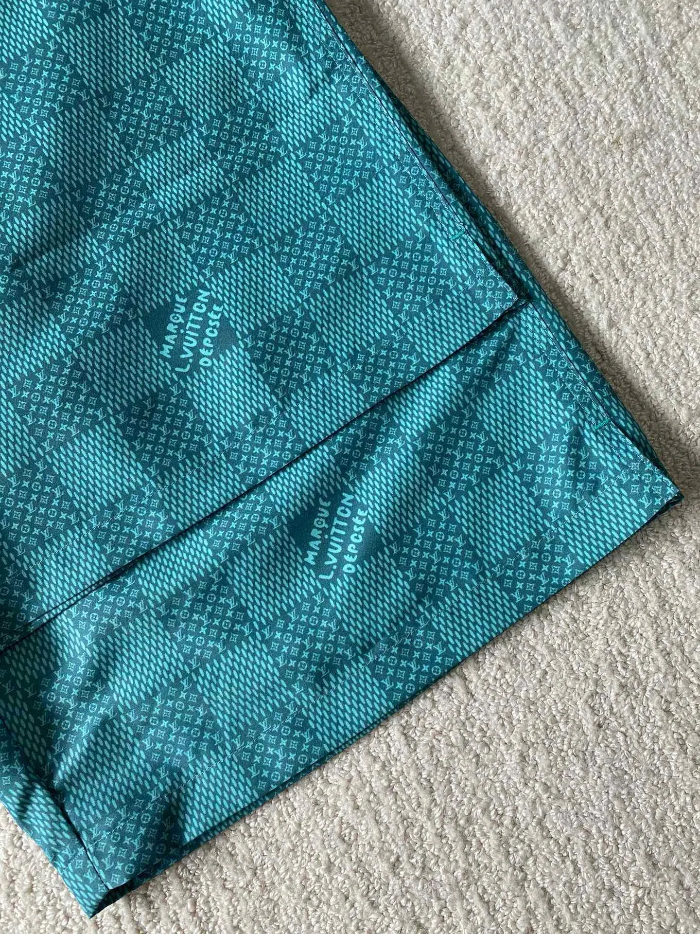 LU green checkerboard beach shorts ⚠️Original purchase, 700, polyester fiber fabric, imported digital printing, cut-piece printing design, standard fit, full-width Damier Monogram printing, drawstring elastic waist #Polyester fiber gray fabric Polyester fiber fabric has excellent wrinkle resistance and shape retention, which allows the shorts to maintain a good appearance after wearing and washing. At the same time, its high strength and good elastic recovery ability ensure the durability of the shorts.  The fabric is very thin and lighter than cotton fiber, so it is very comfortable to wear without feeling tight or compressive. It also has good softness and smooth touch, which increases the wearing comfort.  #Full-width Damier Monogram printing After the entire pattern is processed by image software, the computer control system sprays the printing ink directly onto the fabric through the nozzle of the inkjet printer as required to form the pattern. It is a precise printing controlled by a computer. The digital image is extremely precise. After the digital image is formed, the image is adjusted and printed. After adjusting the image, inkjet printing is performed on a digital printing machine. The ink is directly printed on the surface of the fabric, and the fabric surface penetrates to restore the quality of the original double-sided printing.  #Cut and sew the pattern to restore the original pattern effect. The pattern design is divided into multiple pieces and spliced ​​together, and it also changes due to size changes; even if it is the original version, the splices cannot be perfectly connected. Pieces can only be cut on the same horizontal line, and the patterns on the left and right trouser legs, and the front and rear panels of the entire piece should be arranged on the same horizontal line as much as possible, so that the sewing effect is consistent.  #straight sports shorts version. Fully elastic high waist with adjustable waist size. The front end of the elastic waist rope has an engraved hardware clock. The inner elastic band at the waist is fixed to the outer material through multiple routings, so the elastic band will not flip over even when worn or washed. The zipper pockets are designed with diagonal inserts on both sides; both ends of the pocket are specially machine-knotted, making it strong, durable and washable.