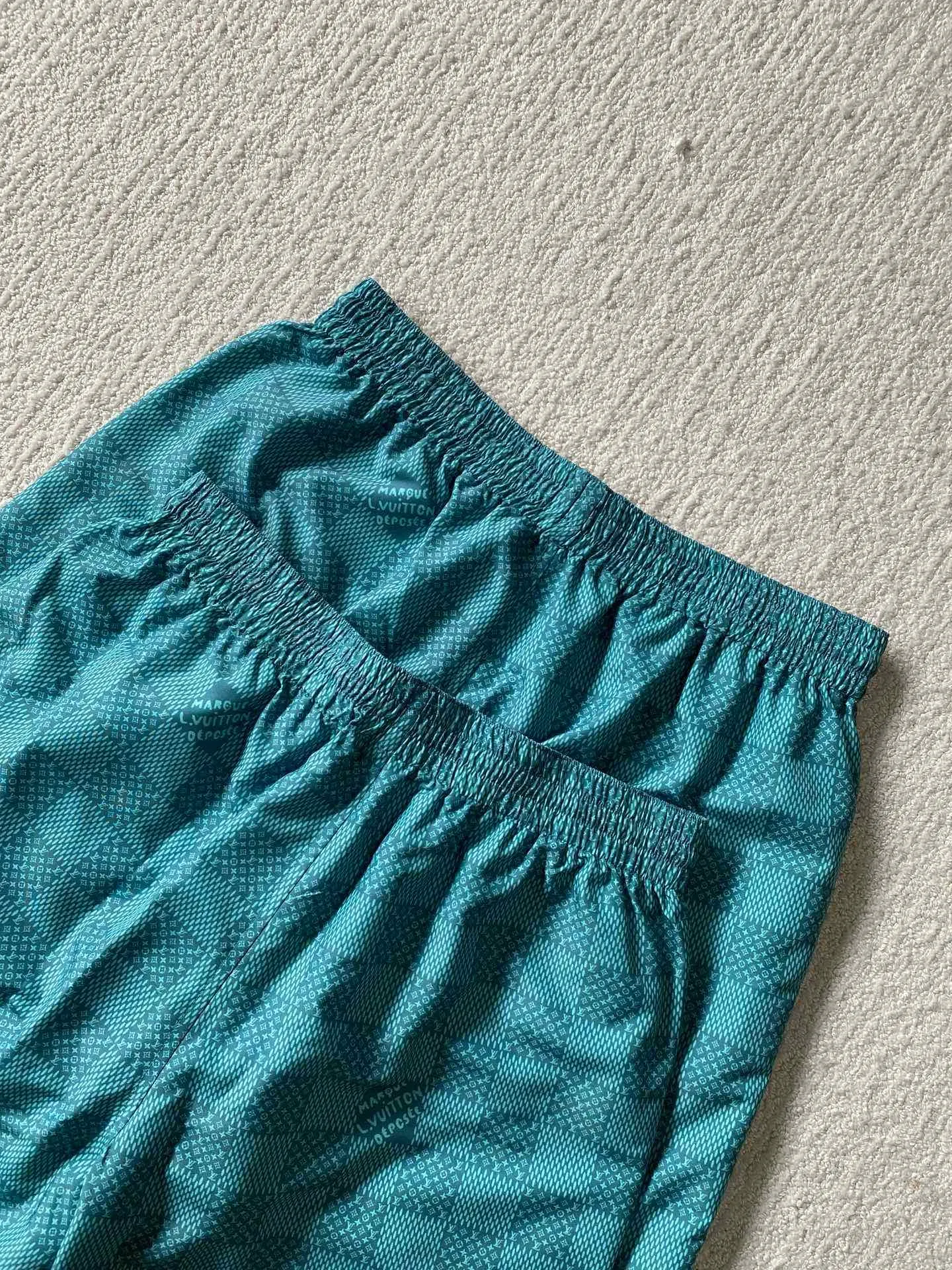 LU green checkerboard beach shorts ⚠️Original purchase, 700, polyester fiber fabric, imported digital printing, cut-piece printing design, standard fit, full-width Damier Monogram printing, drawstring elastic waist #Polyester fiber gray fabric Polyester fiber fabric has excellent wrinkle resistance and shape retention, which allows the shorts to maintain a good appearance after wearing and washing. At the same time, its high strength and good elastic recovery ability ensure the durability of the shorts.  The fabric is very thin and lighter than cotton fiber, so it is very comfortable to wear without feeling tight or compressive. It also has good softness and smooth touch, which increases the wearing comfort.  #Full-width Damier Monogram printing After the entire pattern is processed by image software, the computer control system sprays the printing ink directly onto the fabric through the nozzle of the inkjet printer as required to form the pattern. It is a precise printing controlled by a computer. The digital image is extremely precise. After the digital image is formed, the image is adjusted and printed. After adjusting the image, inkjet printing is performed on a digital printing machine. The ink is directly printed on the surface of the fabric, and the fabric surface penetrates to restore the quality of the original double-sided printing.  #Cut and sew the pattern to restore the original pattern effect. The pattern design is divided into multiple pieces and spliced ​​together, and it also changes due to size changes; even if it is the original version, the splices cannot be perfectly connected. Pieces can only be cut on the same horizontal line, and the patterns on the left and right trouser legs, and the front and rear panels of the entire piece should be arranged on the same horizontal line as much as possible, so that the sewing effect is consistent.  #straight sports shorts version. Fully elastic high waist with adjustable waist size. The front end of the elastic waist rope has an engraved hardware clock. The inner elastic band at the waist is fixed to the outer material through multiple routings, so the elastic band will not flip over even when worn or washed. The zipper pockets are designed with diagonal inserts on both sides; both ends of the pocket are specially machine-knotted, making it strong, durable and washable.