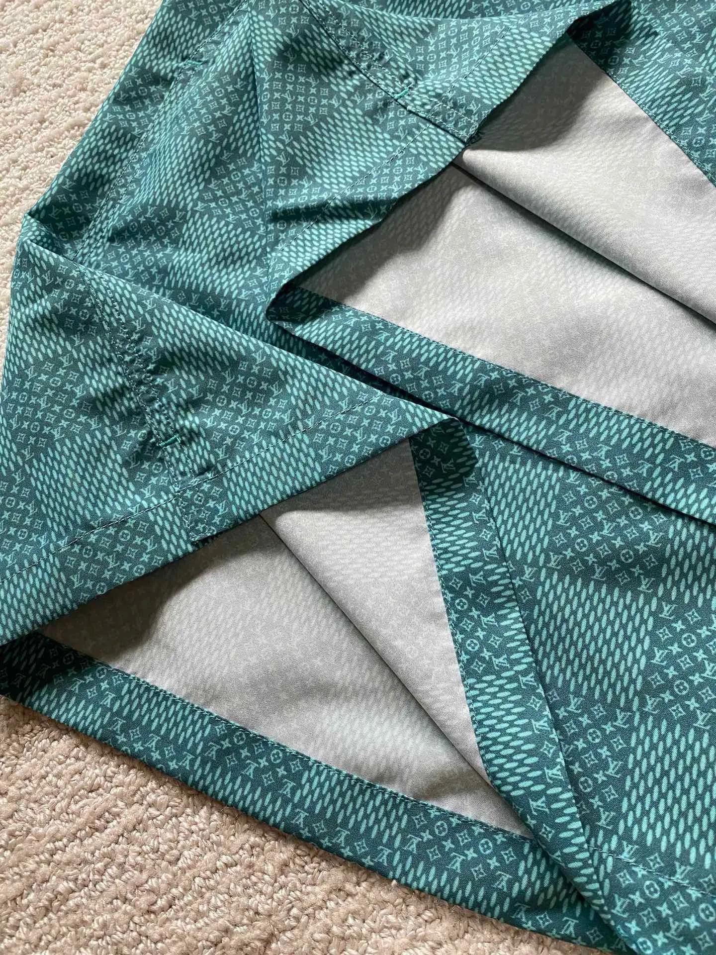 LU green checkerboard beach shorts ⚠️Original purchase, 700, polyester fiber fabric, imported digital printing, cut-piece printing design, standard fit, full-width Damier Monogram printing, drawstring elastic waist #Polyester fiber gray fabric Polyester fiber fabric has excellent wrinkle resistance and shape retention, which allows the shorts to maintain a good appearance after wearing and washing. At the same time, its high strength and good elastic recovery ability ensure the durability of the shorts.  The fabric is very thin and lighter than cotton fiber, so it is very comfortable to wear without feeling tight or compressive. It also has good softness and smooth touch, which increases the wearing comfort.  #Full-width Damier Monogram printing After the entire pattern is processed by image software, the computer control system sprays the printing ink directly onto the fabric through the nozzle of the inkjet printer as required to form the pattern. It is a precise printing controlled by a computer. The digital image is extremely precise. After the digital image is formed, the image is adjusted and printed. After adjusting the image, inkjet printing is performed on a digital printing machine. The ink is directly printed on the surface of the fabric, and the fabric surface penetrates to restore the quality of the original double-sided printing.  #Cut and sew the pattern to restore the original pattern effect. The pattern design is divided into multiple pieces and spliced ​​together, and it also changes due to size changes; even if it is the original version, the splices cannot be perfectly connected. Pieces can only be cut on the same horizontal line, and the patterns on the left and right trouser legs, and the front and rear panels of the entire piece should be arranged on the same horizontal line as much as possible, so that the sewing effect is consistent.  #straight sports shorts version. Fully elastic high waist with adjustable waist size. The front end of the elastic waist rope has an engraved hardware clock. The inner elastic band at the waist is fixed to the outer material through multiple routings, so the elastic band will not flip over even when worn or washed. The zipper pockets are designed with diagonal inserts on both sides; both ends of the pocket are specially machine-knotted, making it strong, durable and washable.
