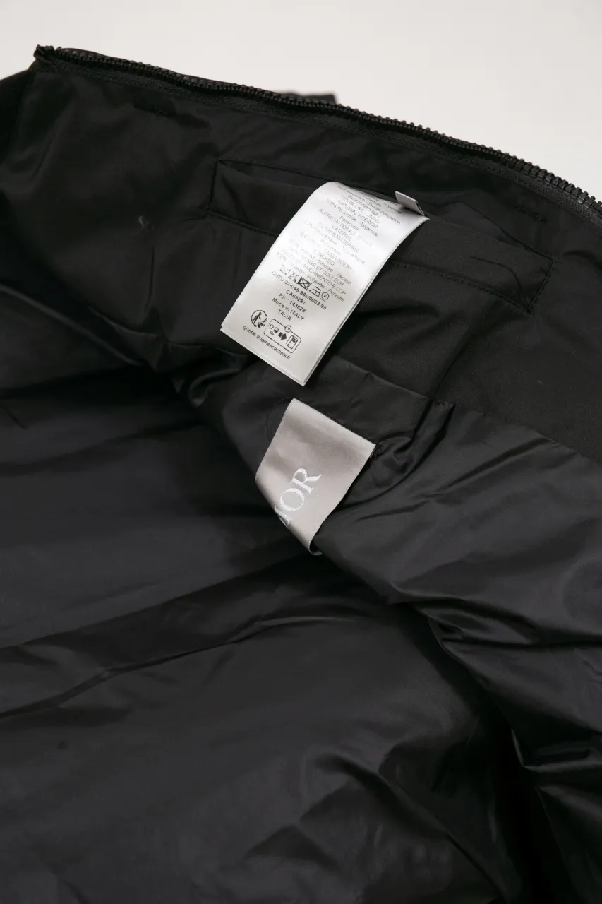 DIOR AND LEWIS HAMILTON JACKET Black technical fabric with removable sleeves This jacket is from the DIOR AND LEWIS HAMILTON limited series. Crafted from black technical fabric and embellished with DIOR AND LEWIS HAMILTON embroidery, the graphic design highlights the iconic Dior signature. With detachable sleeves, it can be worn in two different ways. It can be paired with jeans to create a low-key sporty look. DIOR AND LEWIS HAMILTON Embroidery and zip Knitted collar Detachable sleeves Front and internal flapless pockets Body: 100% nylon, Lining: 100% nylon